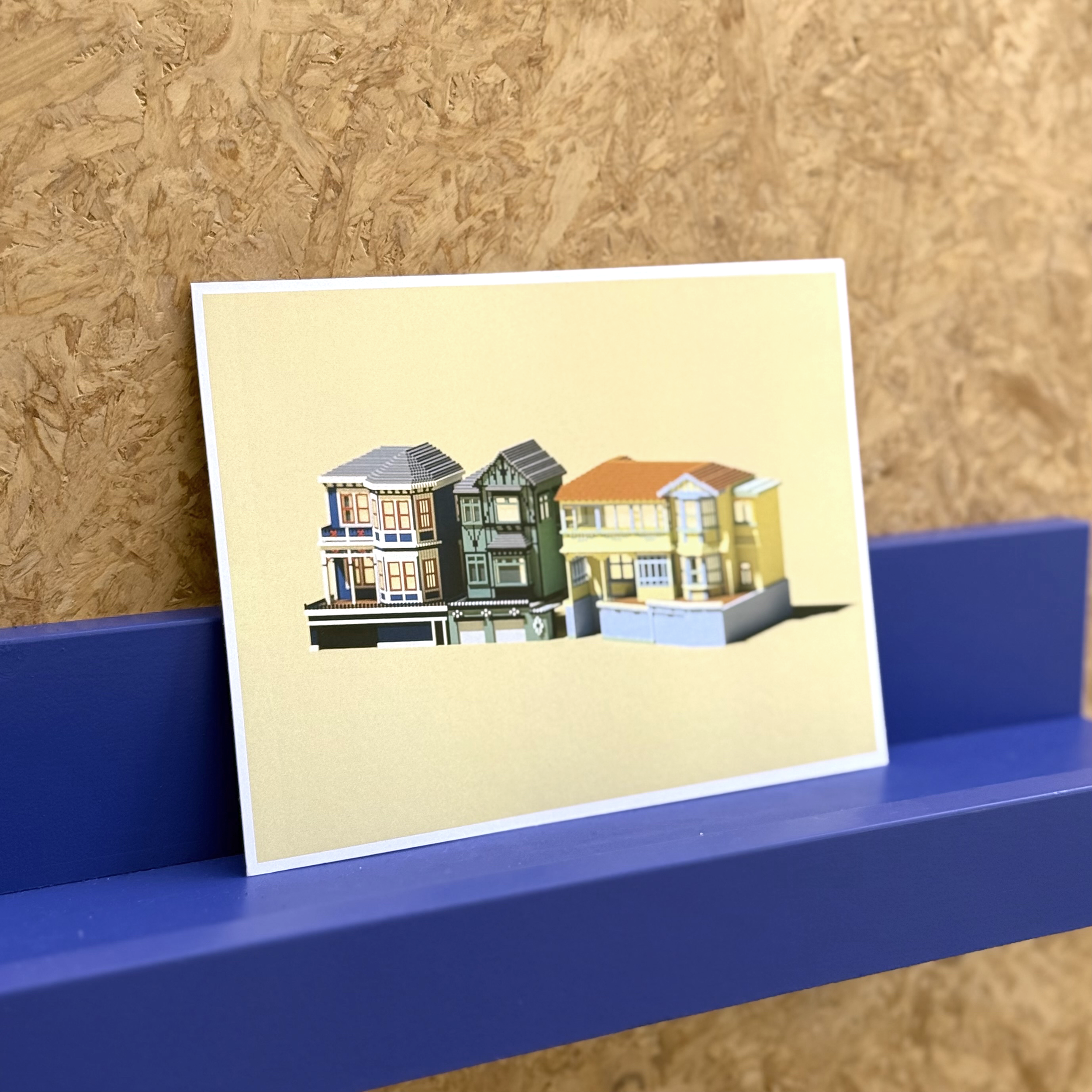 Oriental Parade Wellington waterfront art print leaning against an ultramarine blue picture rail on a chipboard wall, part of the Welly Pixels series by Nicole Keane