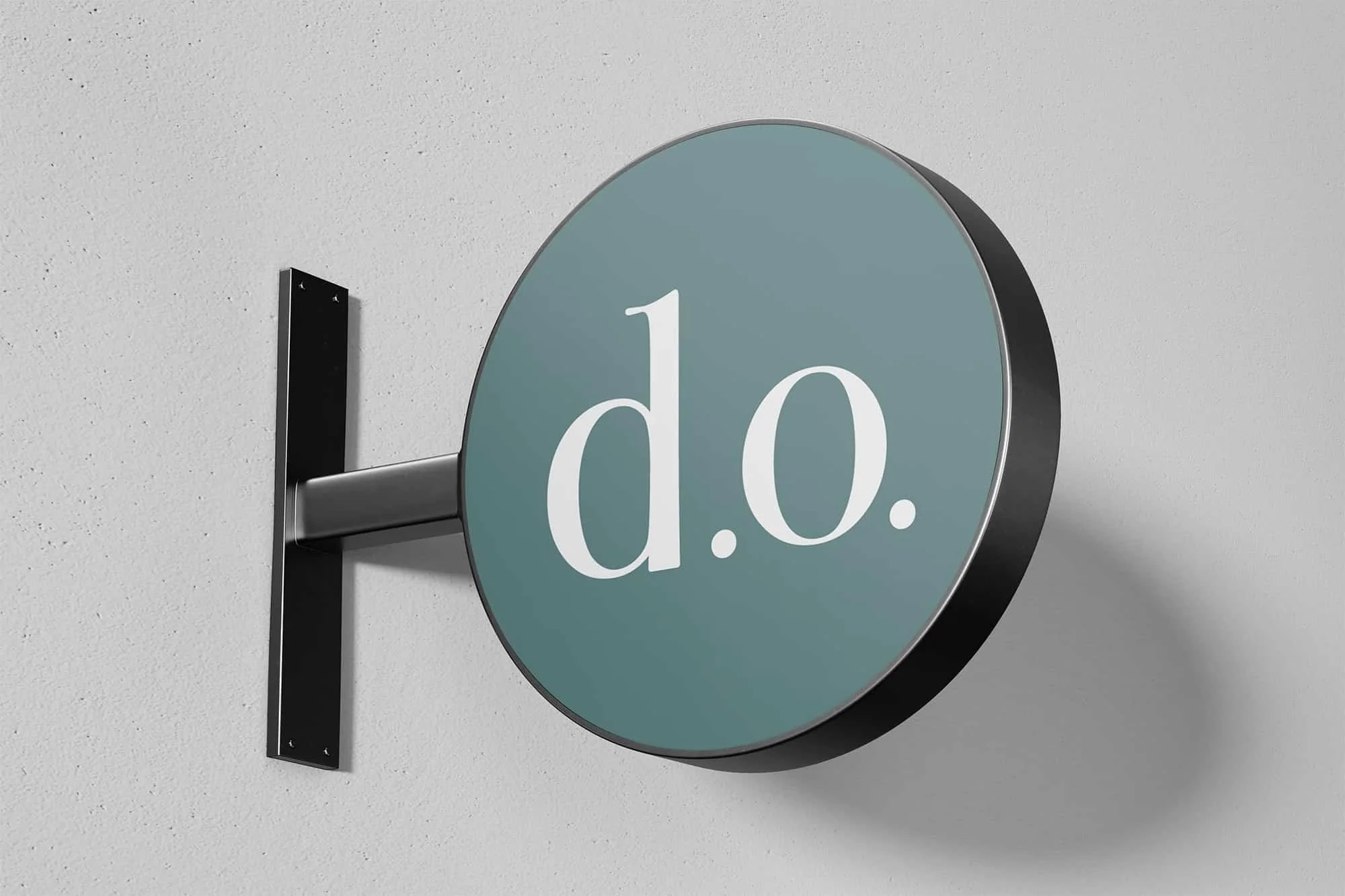 Round gray sign with white text reading 'd.o.' mounted on a black wall bracket against a white wall.