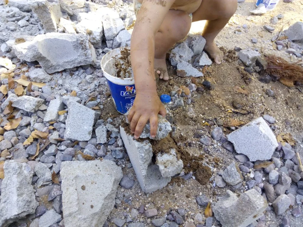 child playing with block and making pretend cement