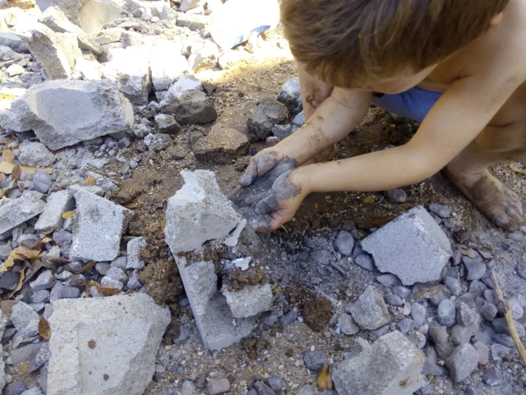 child playing with block and making pretend cement