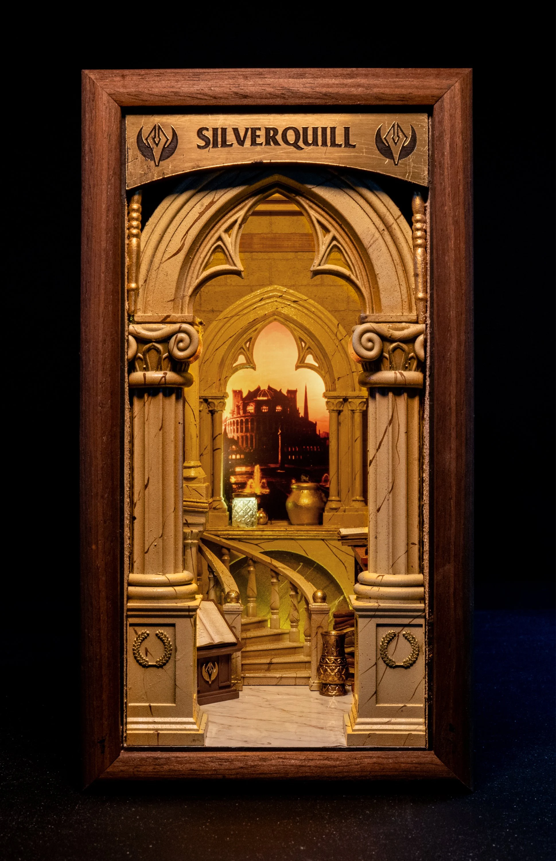 A miniature diorama of an ornate, classical interior with columns, decorative objects, and a distant view of the Roman Colosseum at sunset framed within a wooden display case.