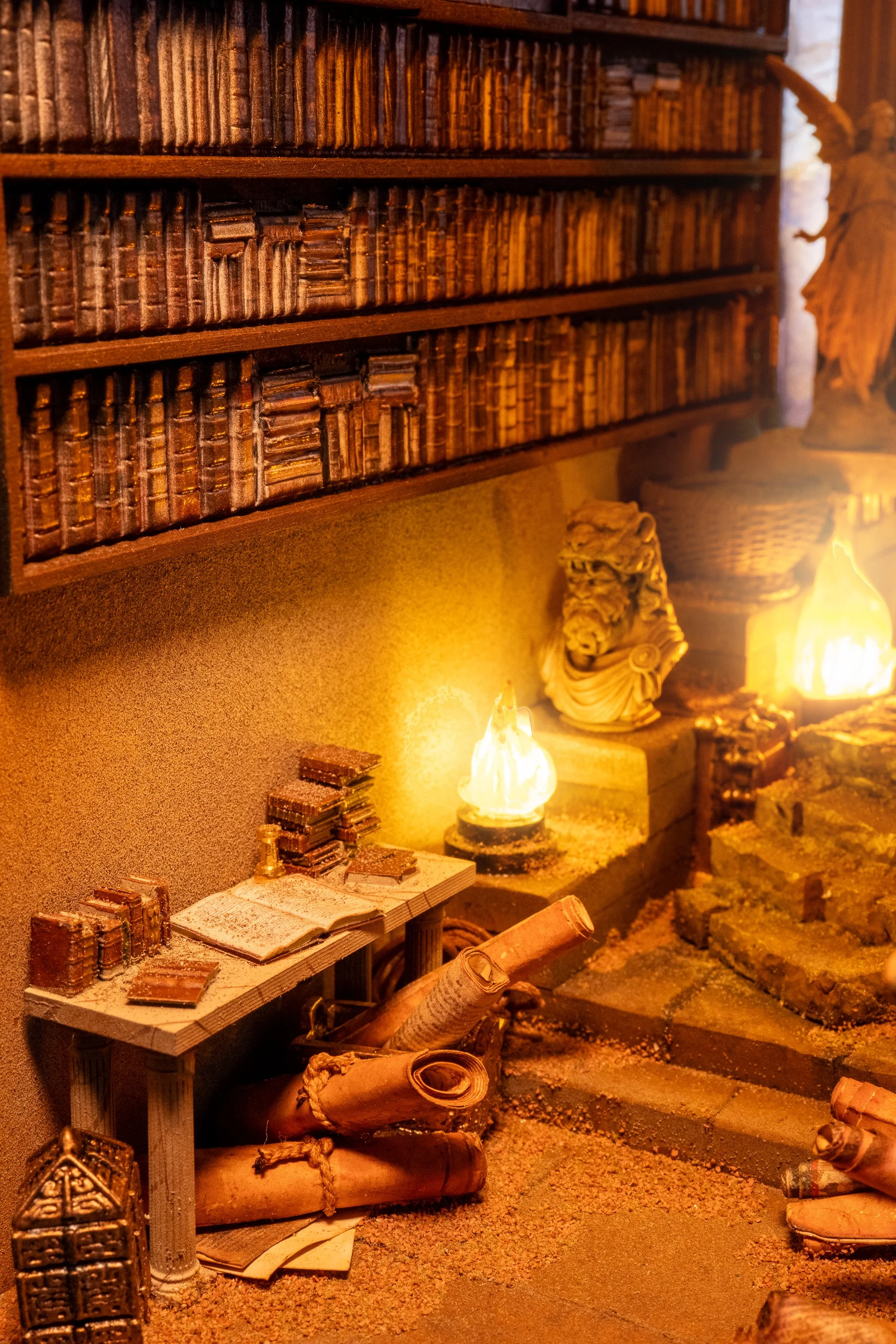 A vintage library or study room with wooden shelves filled with old books, a small table with more books, and a fireplace with a glowing fire. Decorative items include a lion sculpture, rolled scrolls, and a telescope.
