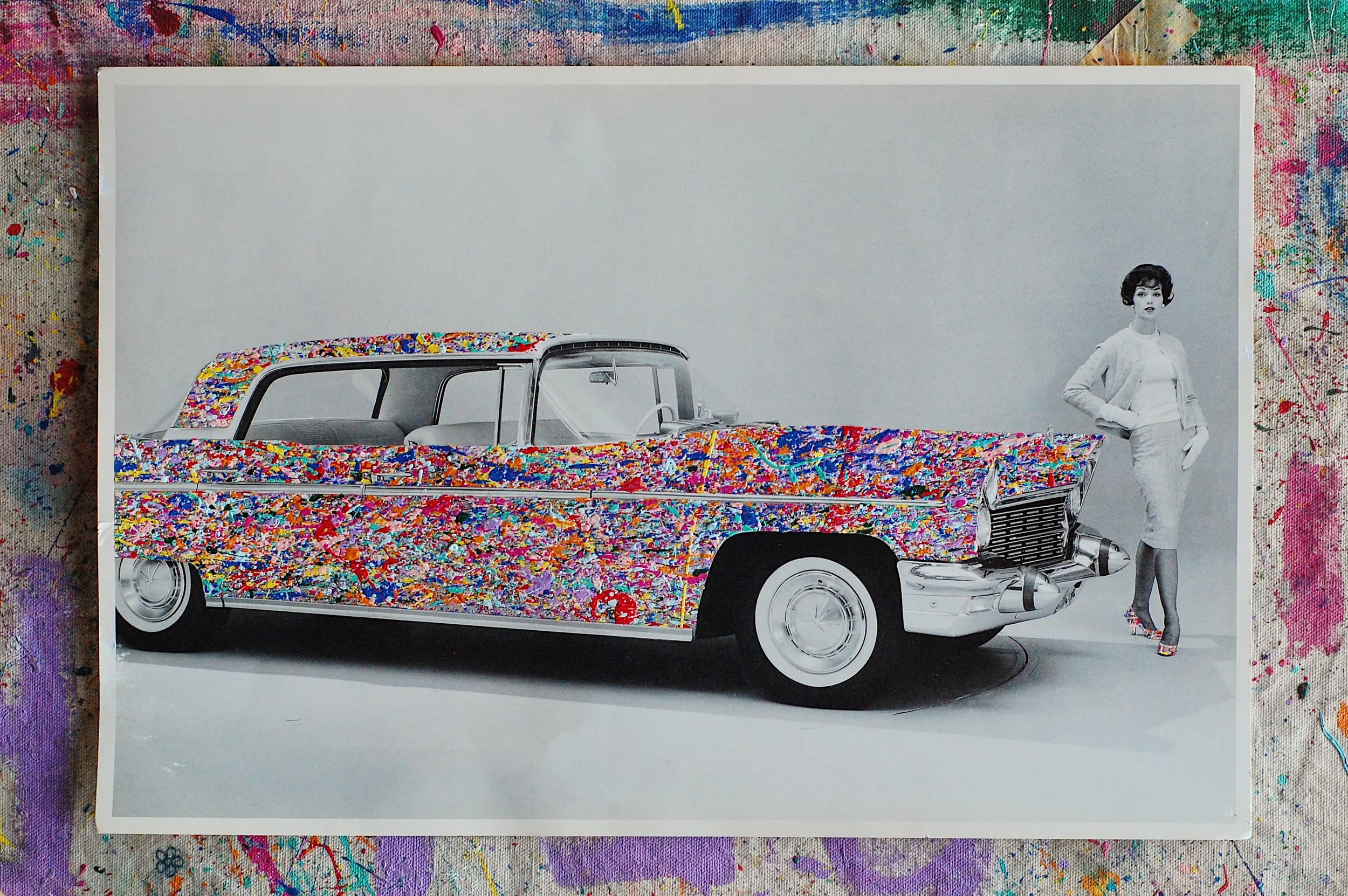 SUPERBLOOM artwork featuring a 1960 Lincoln Continental transformed with expressive paint splatter, photographed on a studio floor with visible artistic textures by SUPERBLOOM