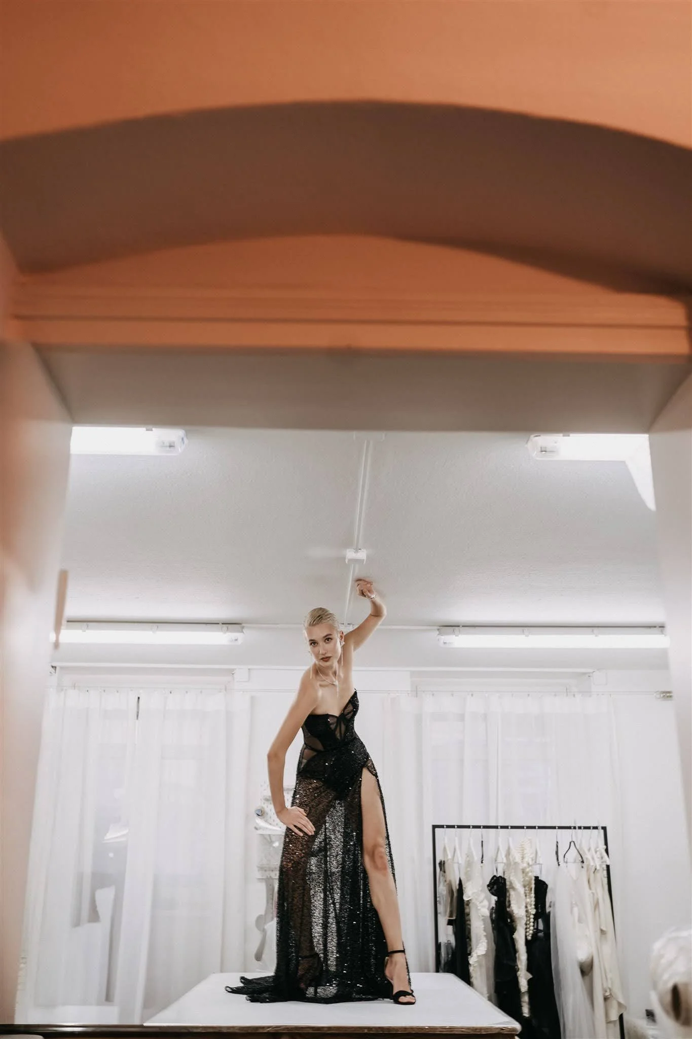 Model wearing a black couture dress standing on the cutting table inside the Berlin couture atelier