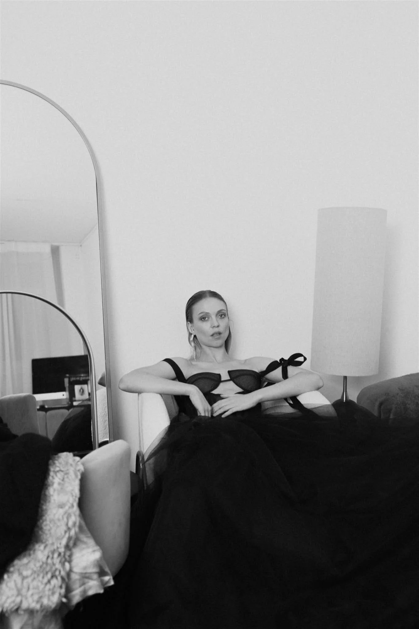 Model wearing a black couture dress seated in the showroom lounge of the Berlin atelier
