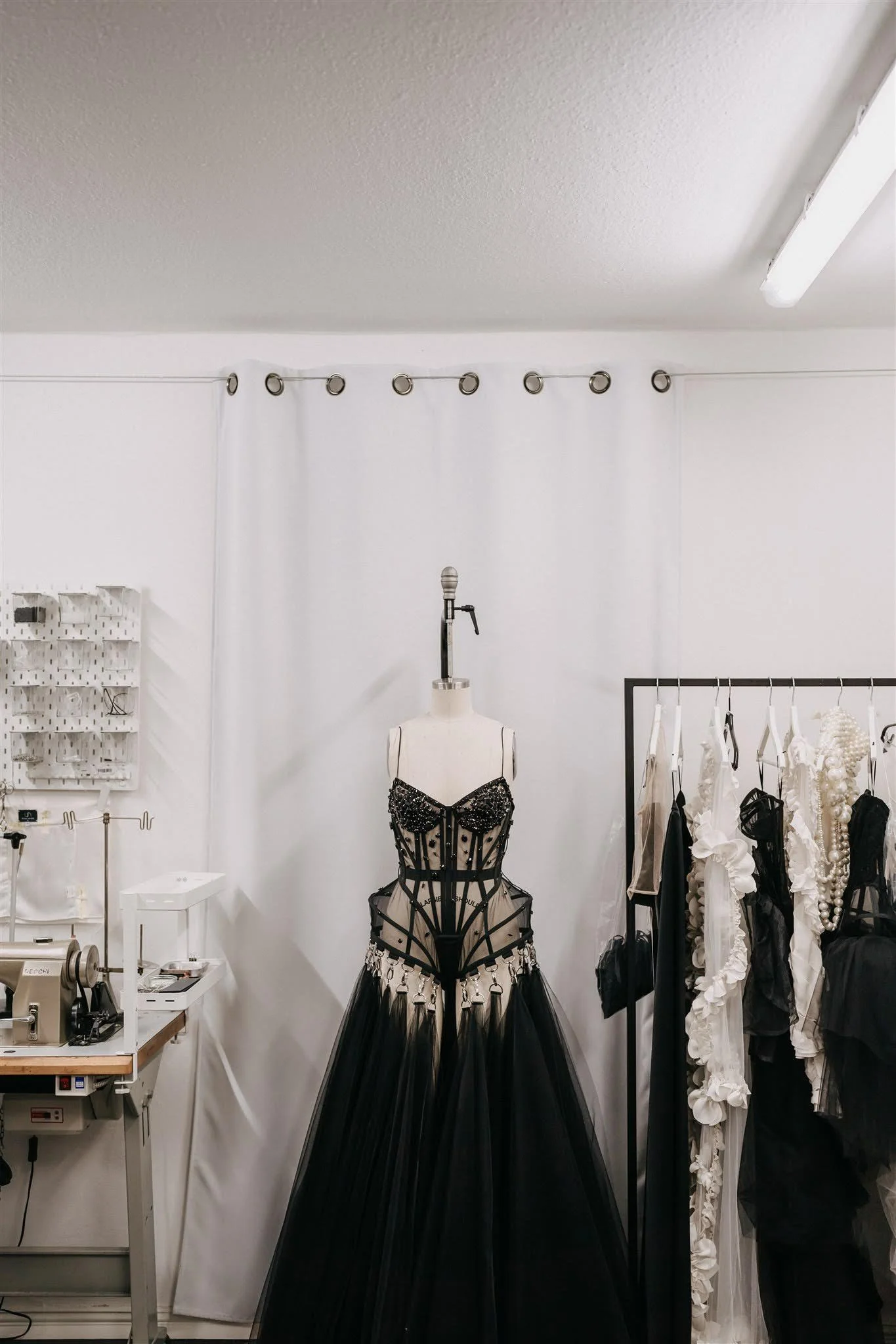 Black couture dress on a mannequin in the Berlin atelier next to a sewing machine and clothing rack