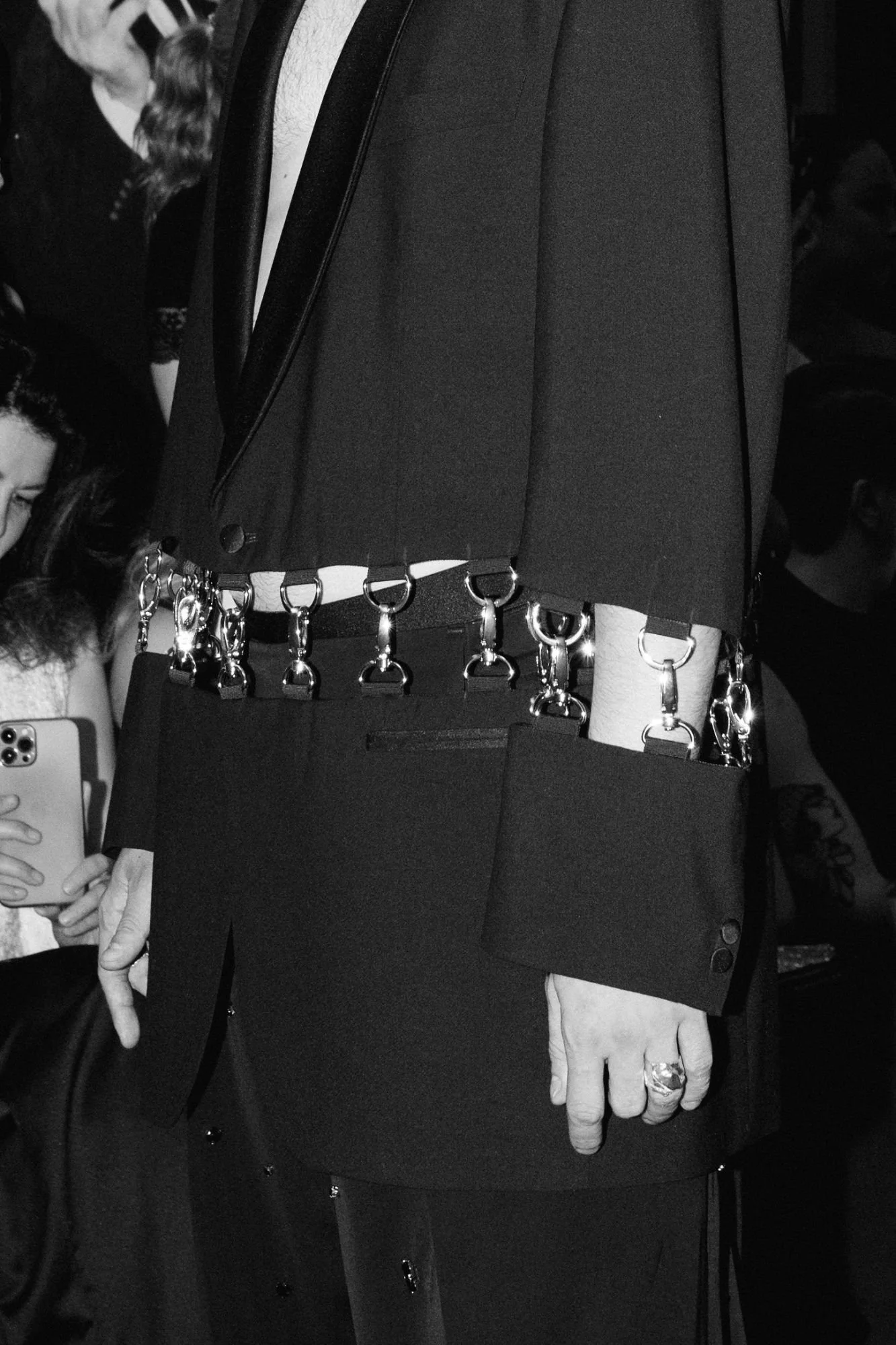 Male model wearing a black bondage-inspired couture suit with waist cut-out and silver hook details