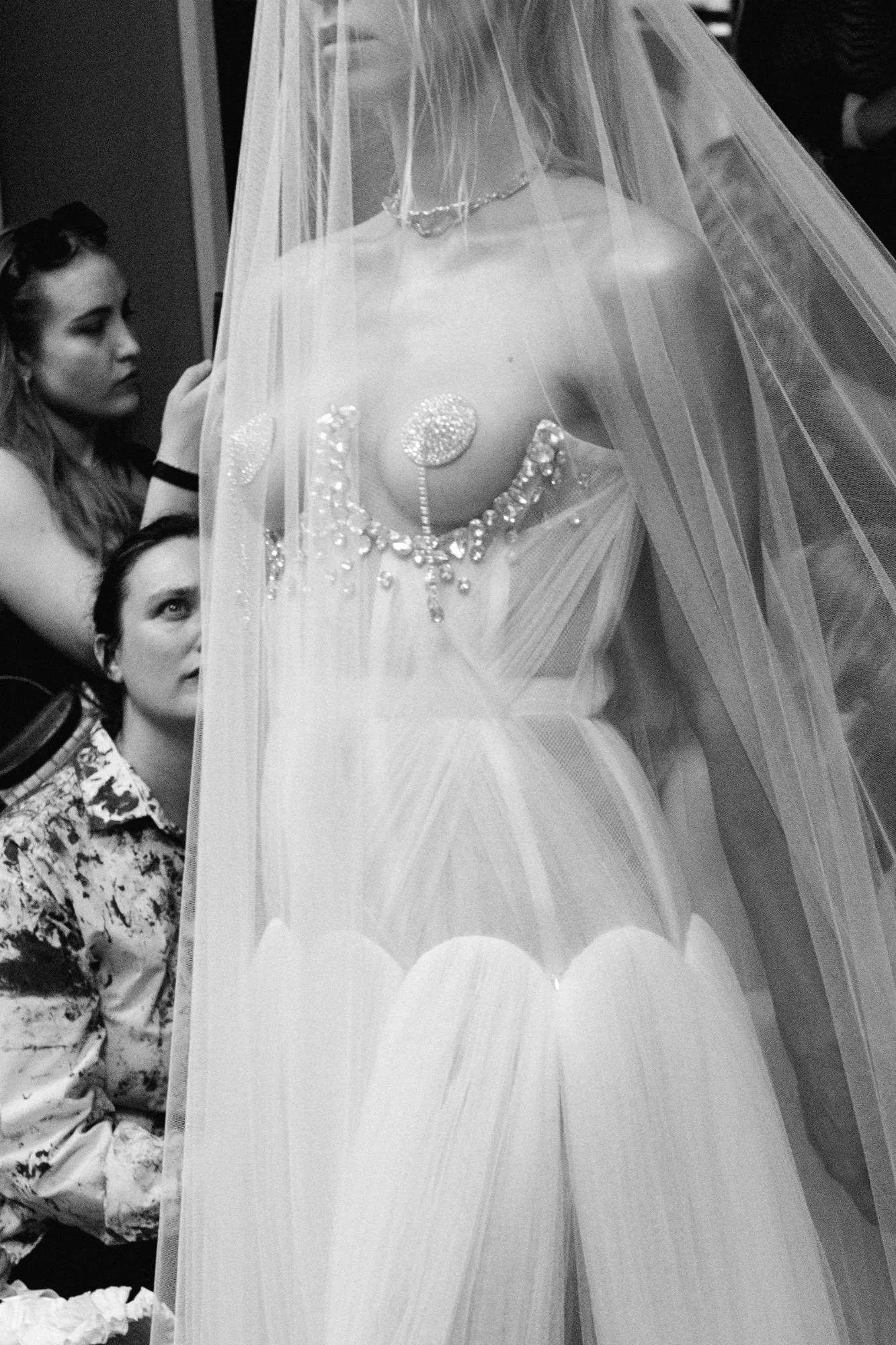 Model wearing an ethereal white couture dress with delicate draping, rhinestone embroidery and an open chest