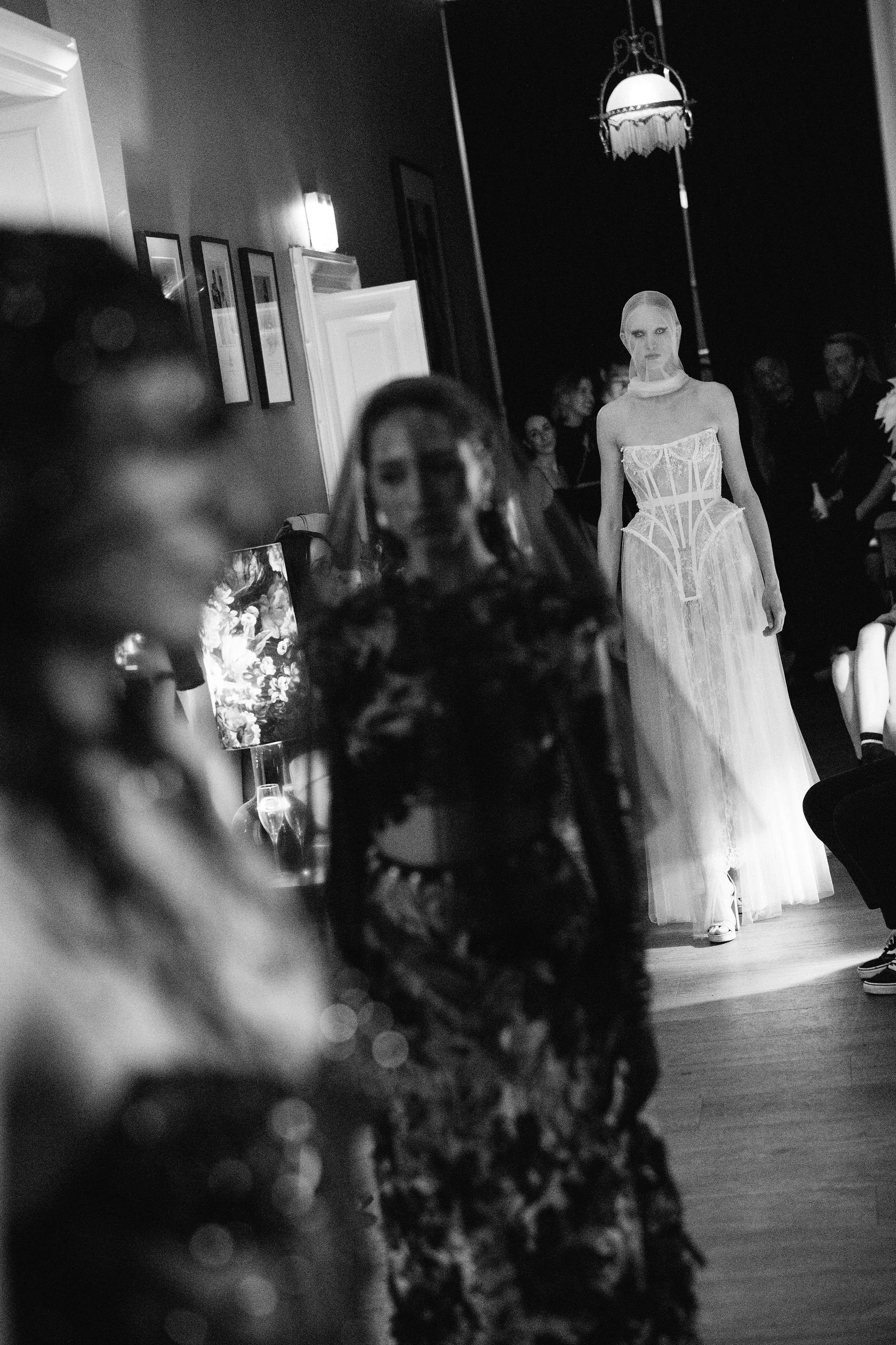 Three models walking in a row during a couture runway show finale wearing bold avant-garde designs
