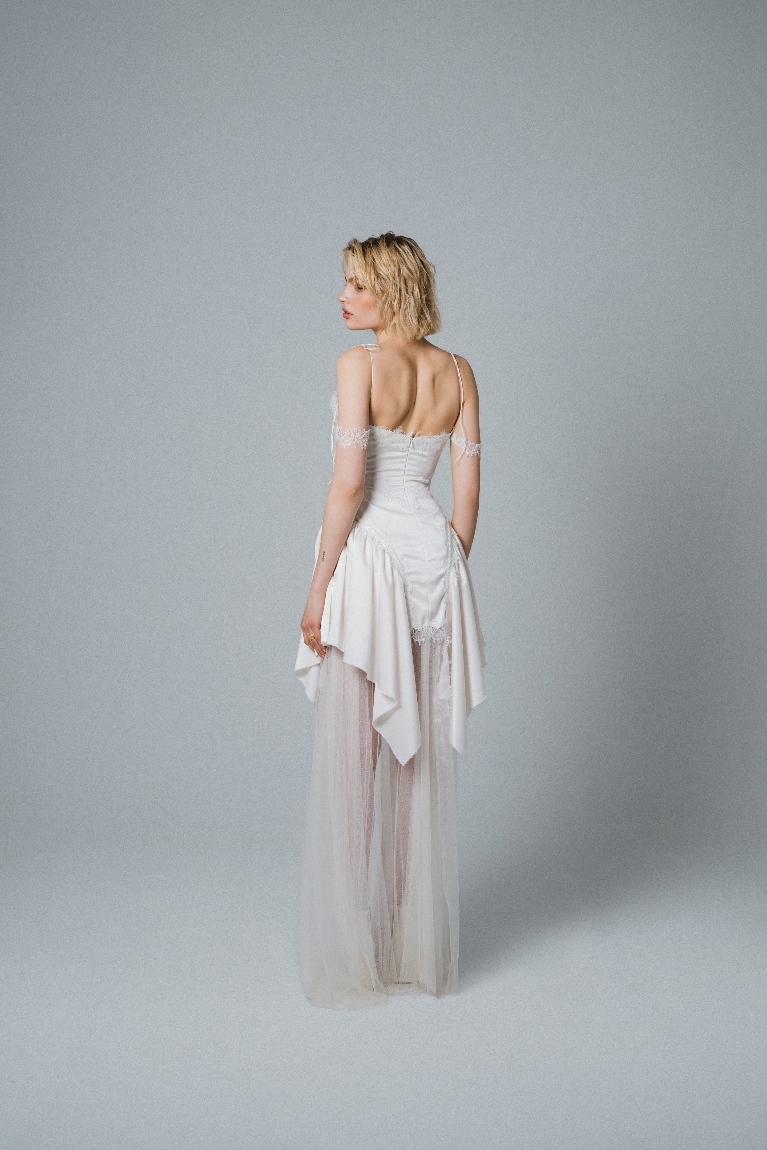 Back view of playful ivory bridal mini dress with flowing asymmetrical skirt