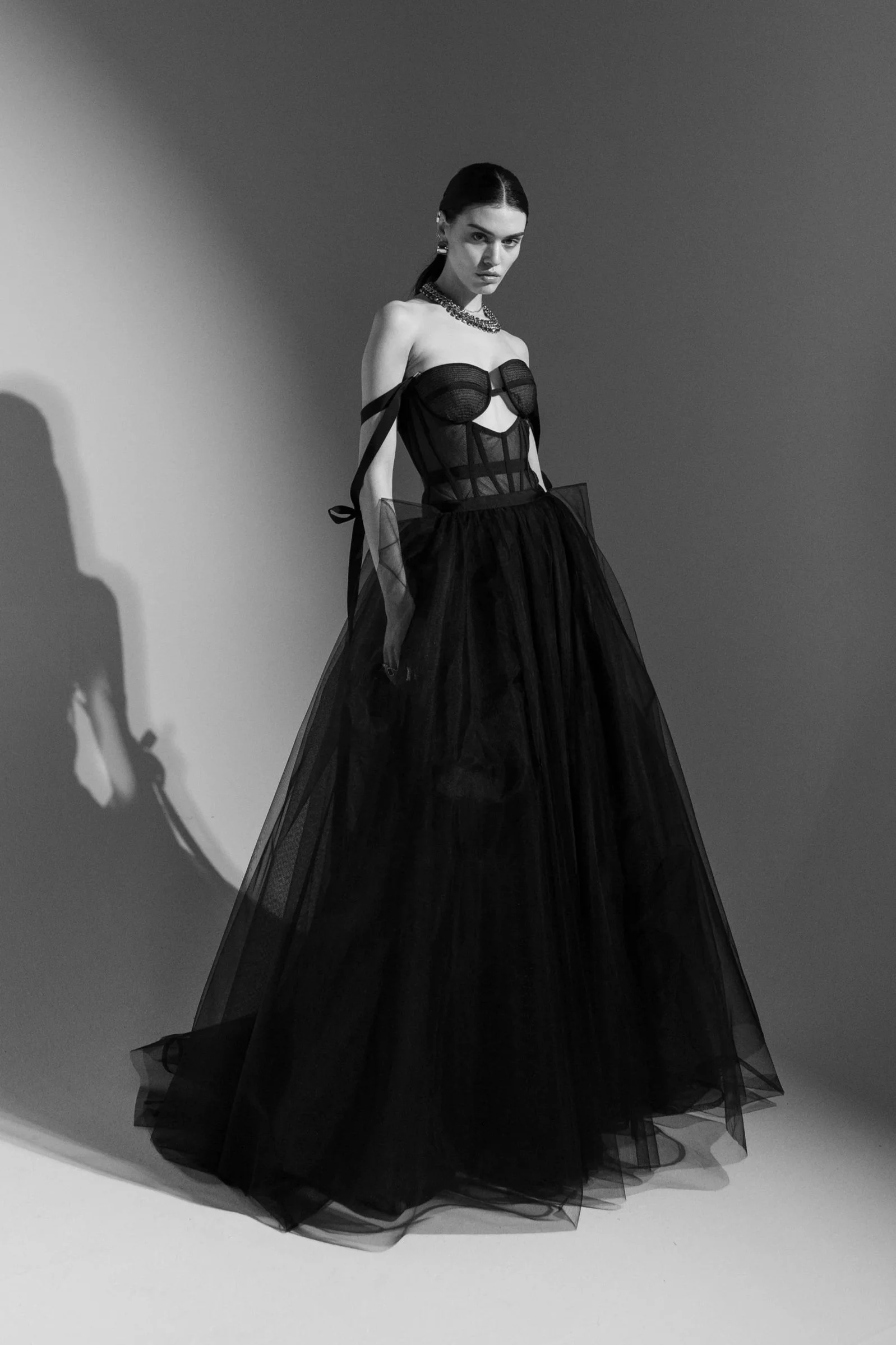 Full-body editorial shot of a black couture evening gown with dramatic silhouette