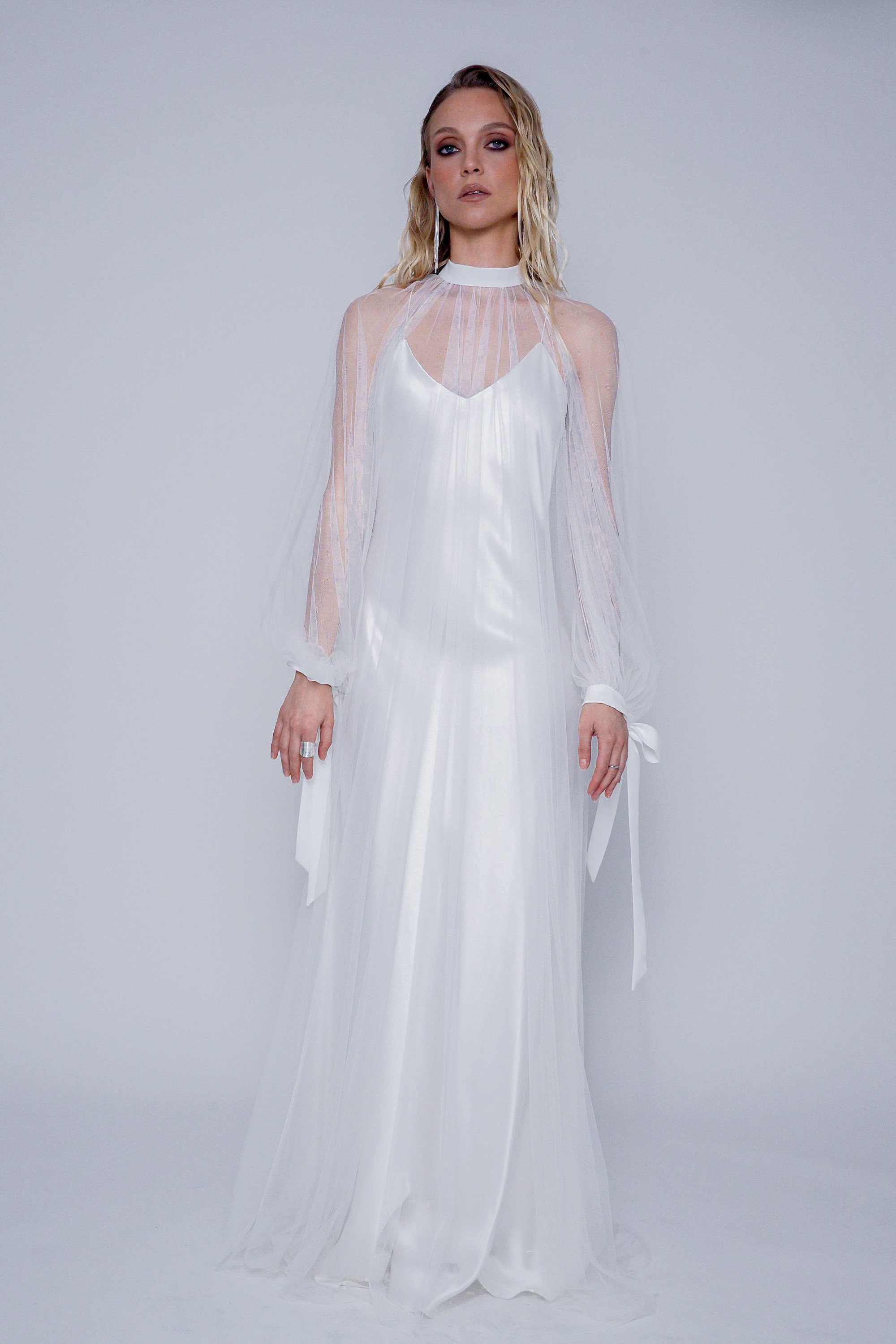 Front view of the Breeze Cape styled over Yaiza Gown, showing puff sleeves and bow tie