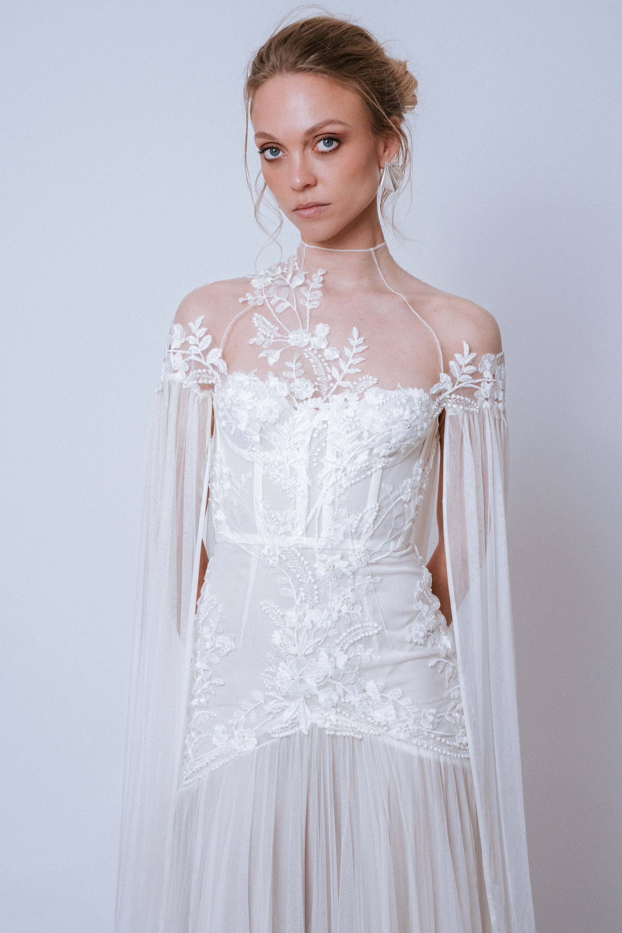 Close-up of the Jen Gown bodice showing lace appliqués, visible corset boning, and sheer shoulder detail