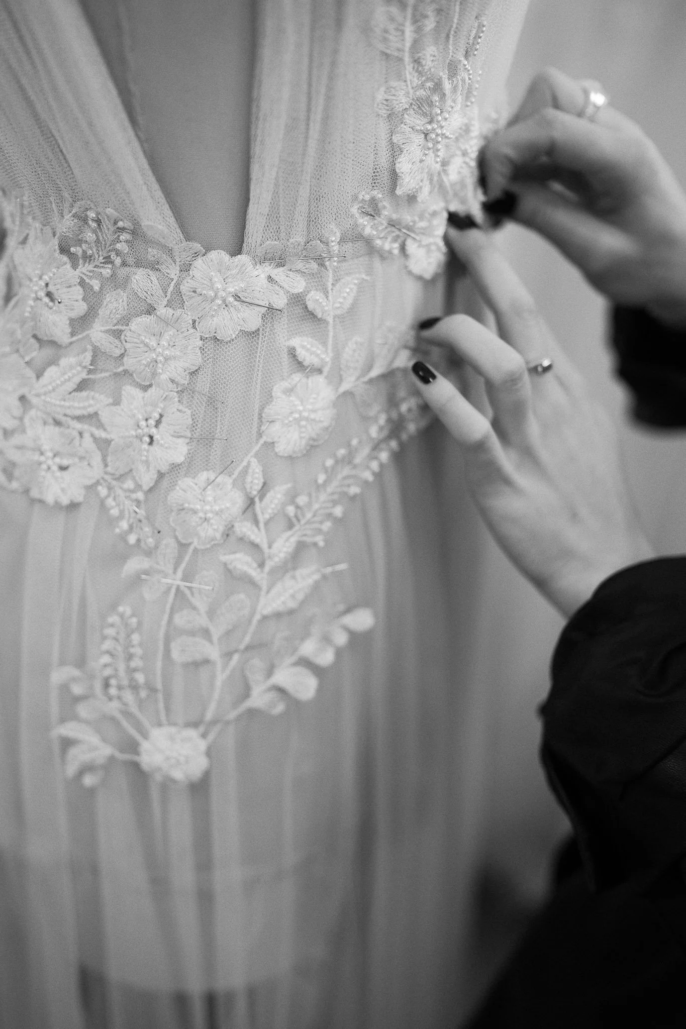 Hands sewing lace by hand onto a bridal couture dress on a mannequin