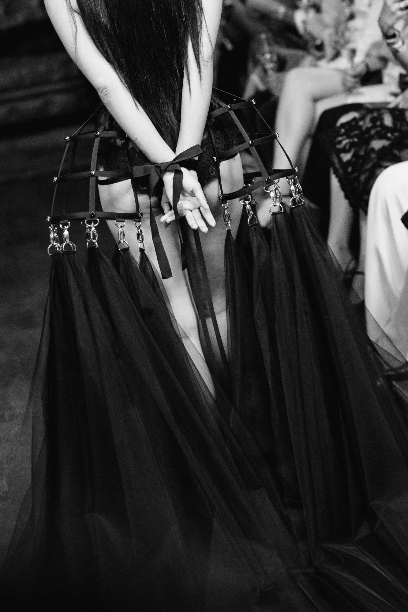 Back view of a couture showpiece with tied hands and a black crinoline skirt