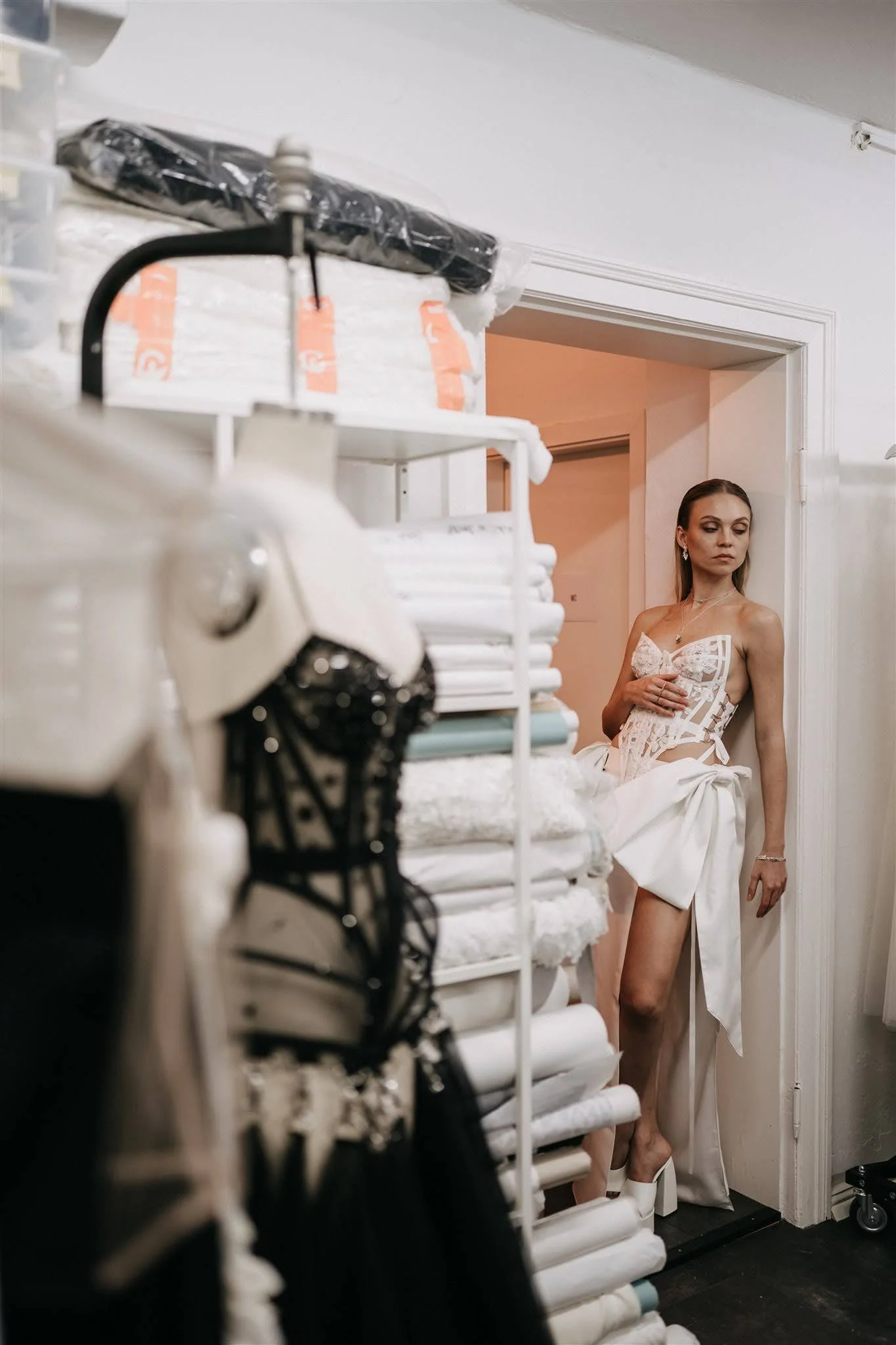 Model wearing a modern bridal two-piece in the Berlin couture atelier beside a mannequin and fabric rack