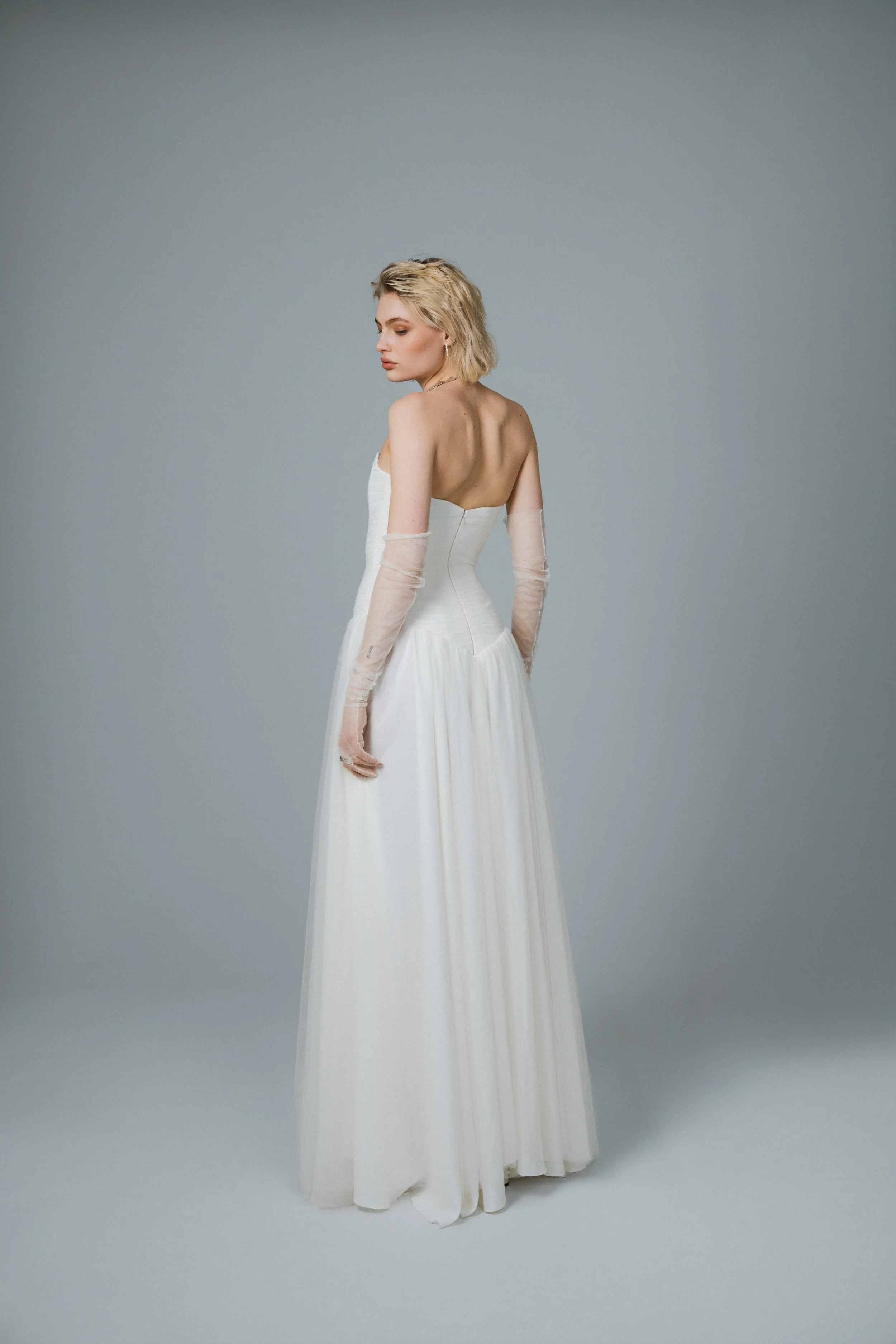 Back view of romantic ivory bridal gown with pointed dropped waistline and soft tulle skirt