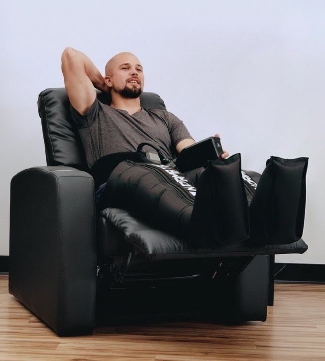 Relaxed man sitting in recliner using Normatec Legs on both his legs