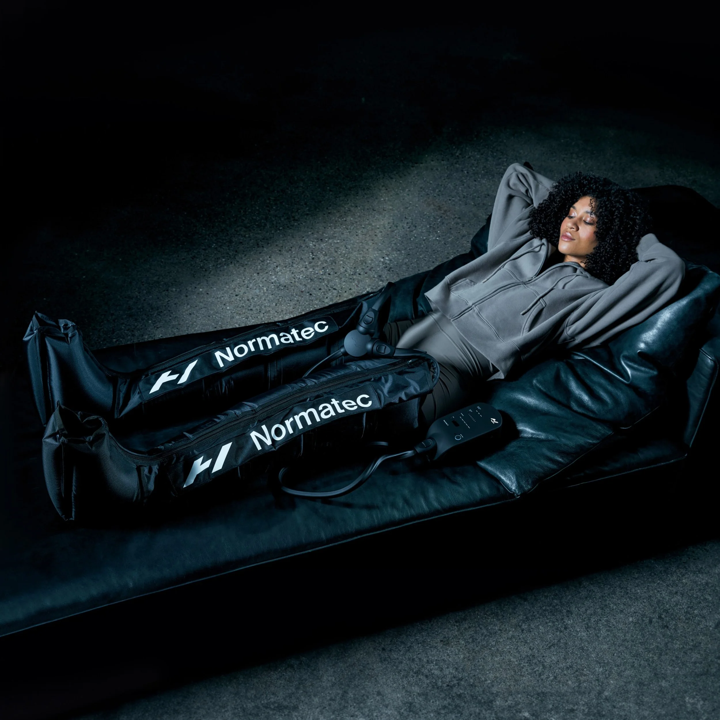 Woman laying back in recliner using Normatec legs on both of her legs