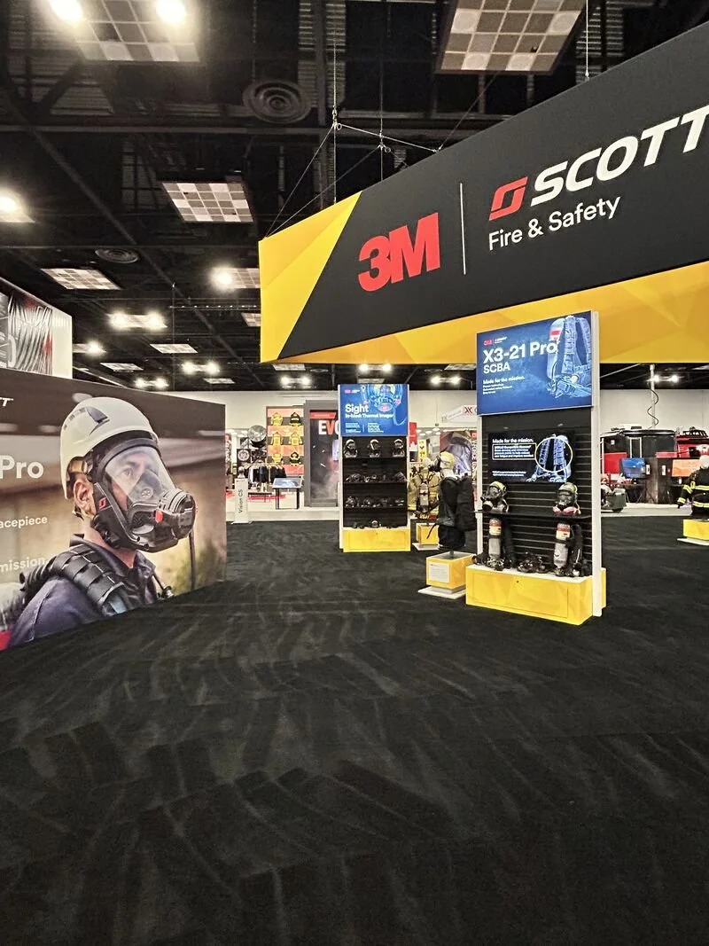 Trade show booth for 3M and Scott Fire & Safety featuring helmets, masks, and safety gear on display with signage.