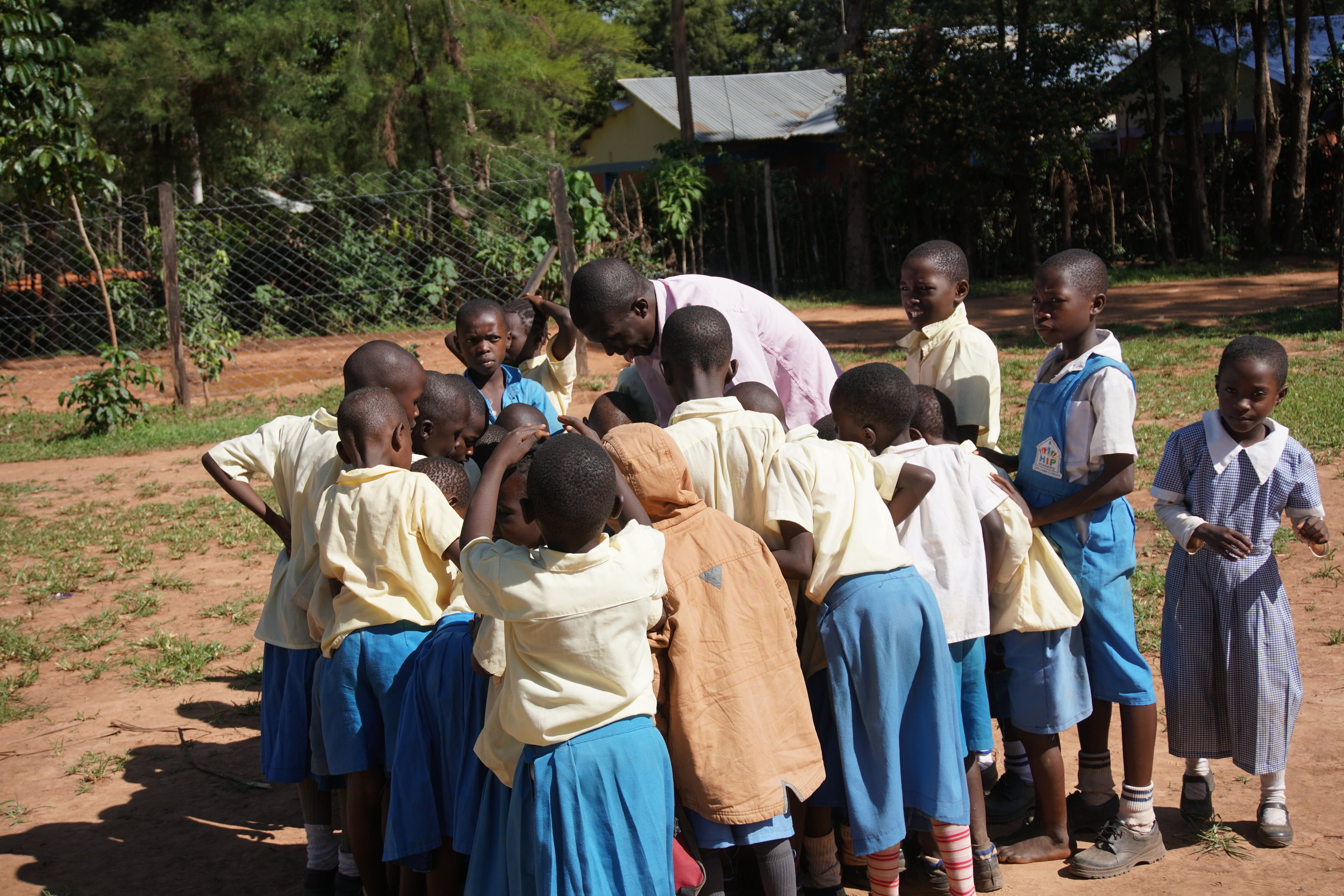 One of HIP's amazing teachers, Jobe, shows his class something while they take a break and go outside.