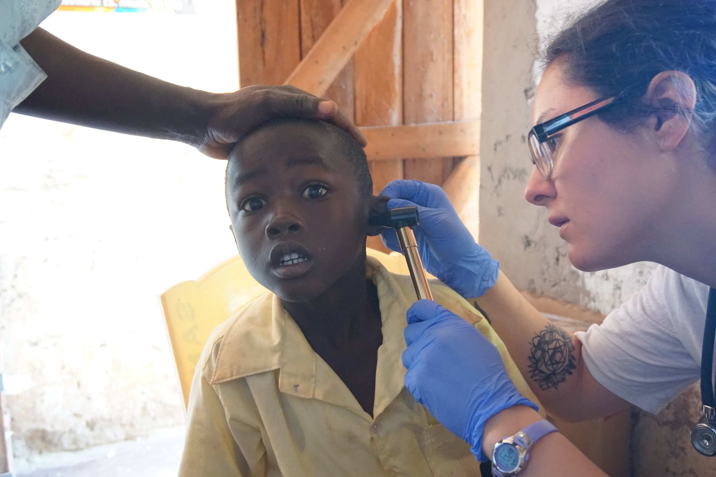  Brooke checks the ears of one of HIP's students. The otoscope was cold and the student wasn't sure what to make of it being in his ear. 