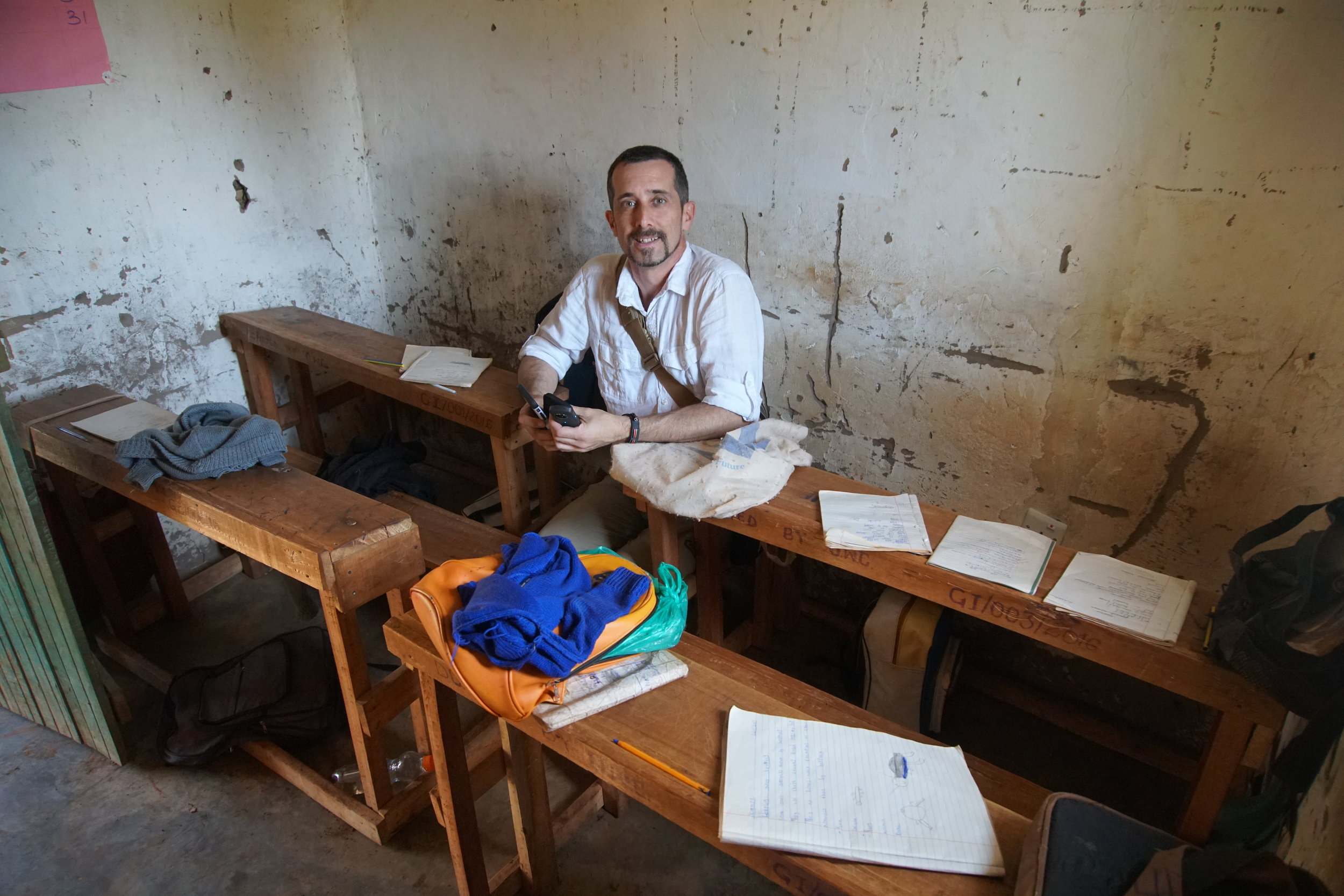  John sits between two tables to show how narrow the isle was for students to walk around. This picture truly does a wonderful job of showing us how small some of the classes were. Right in front of one of the tables, you cam see the open door to the