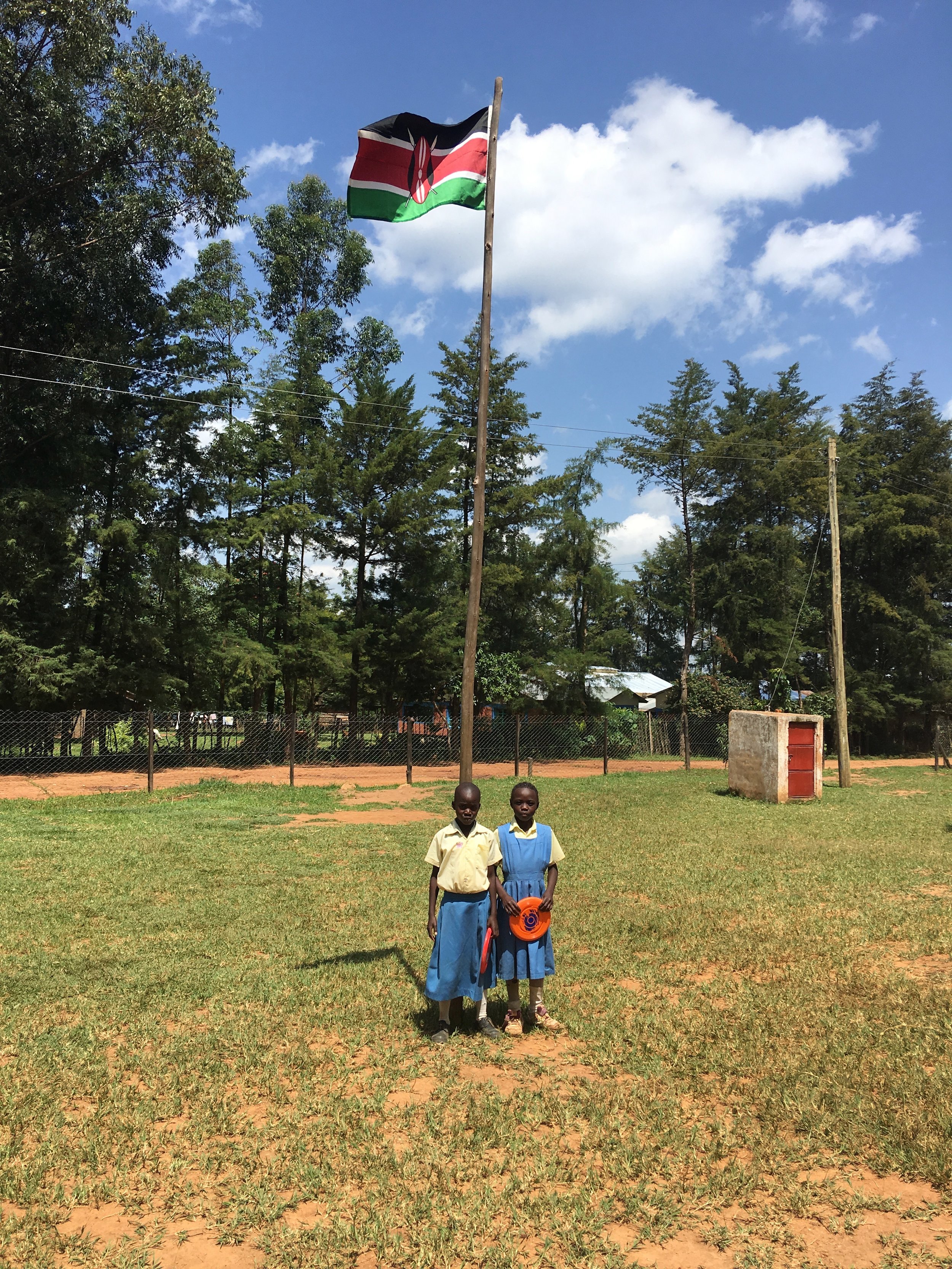  Two students posing in front of the Kenyan flag. 