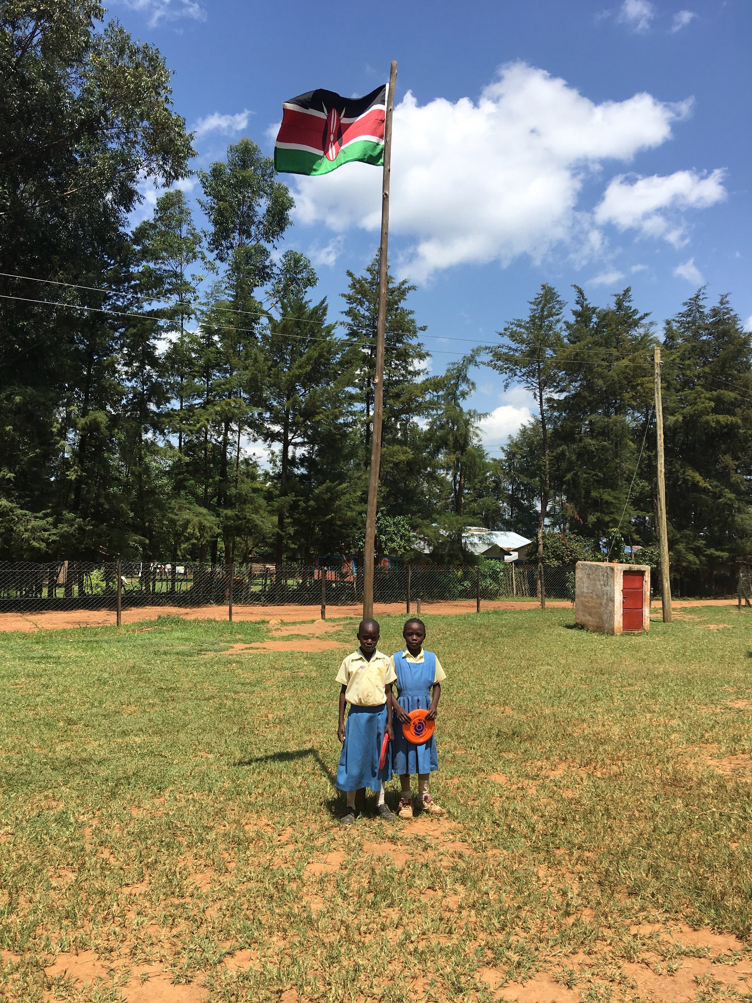 Two students posing in front of the Kenyan flag.