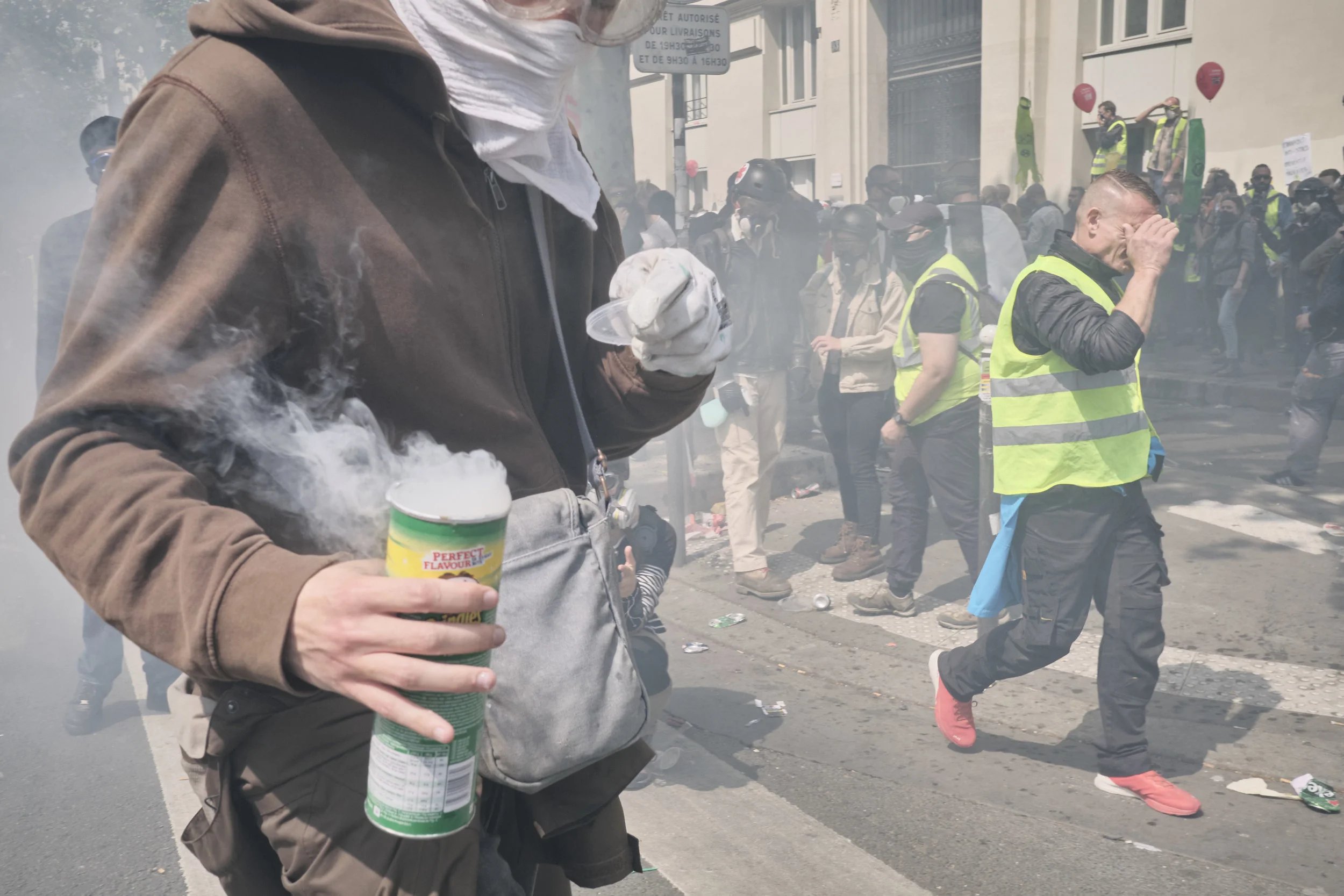 Protest participant collecting tear gas grenades and storing them in a “Pringles” container during the police attempt to control the crowd at Boulevard du Montparnasse.
