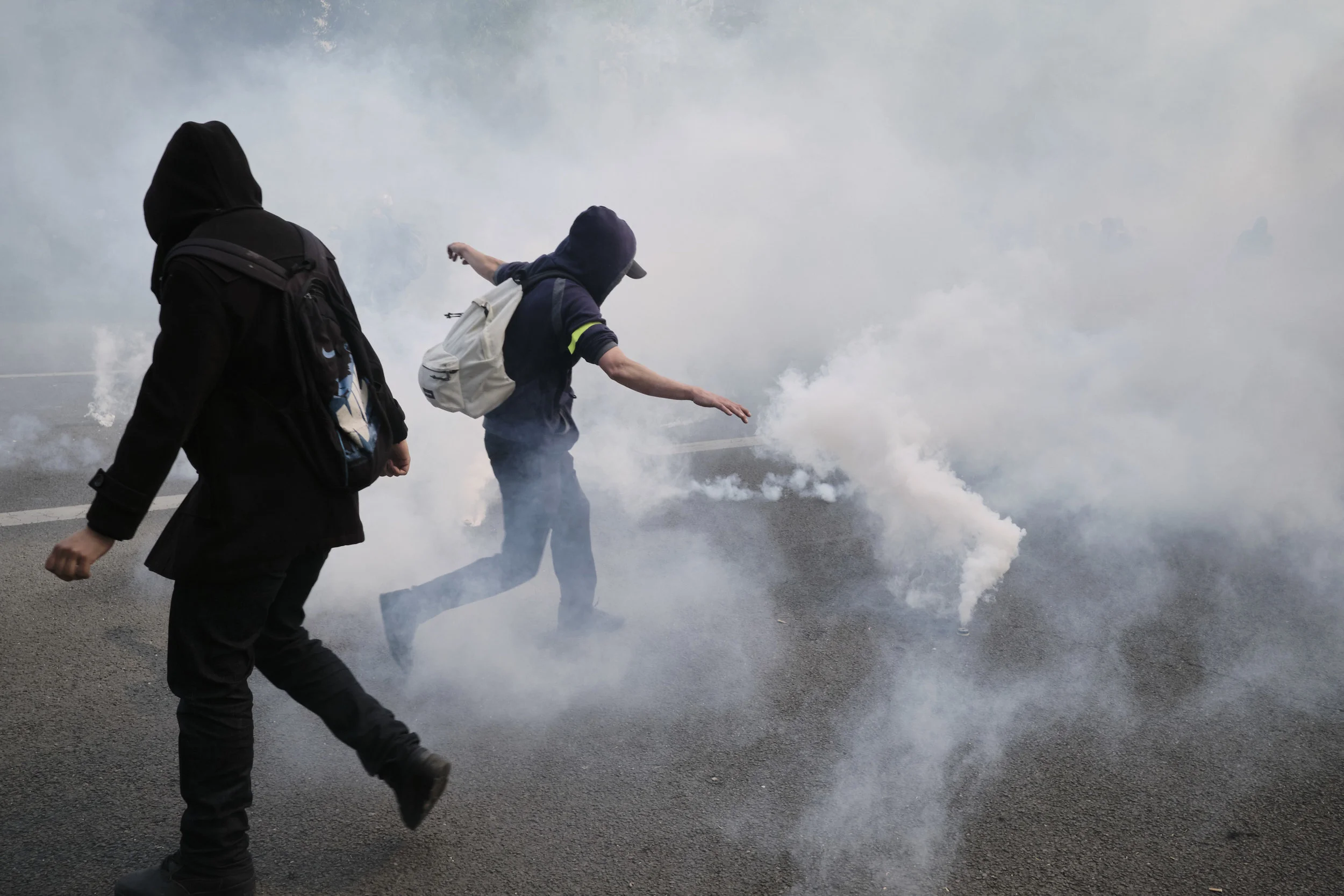 Protesters kicking tear gas grenades away from the crowd of protesters towards the police during a confrontation. 