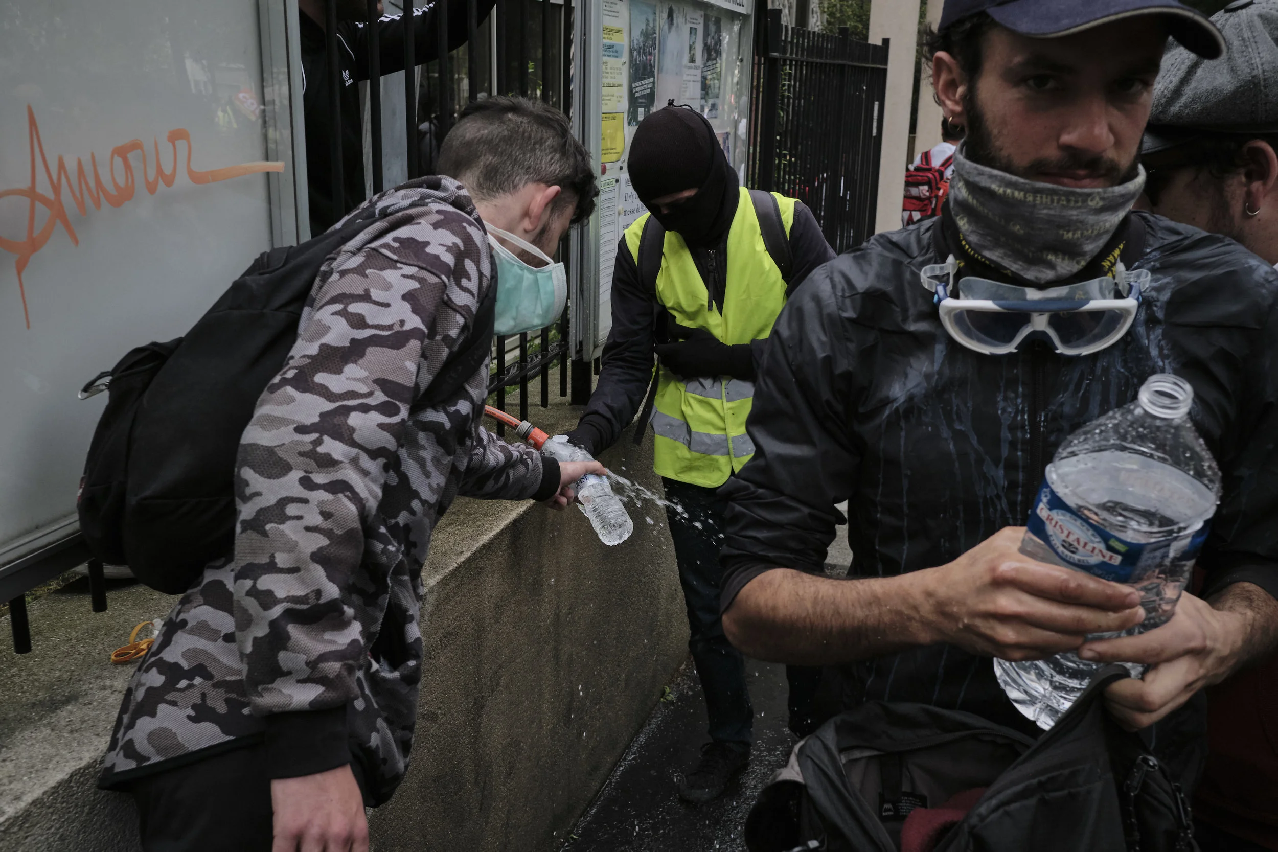 Protest participants filling up their water bottles from a garden hose during their march to Place D'italie.