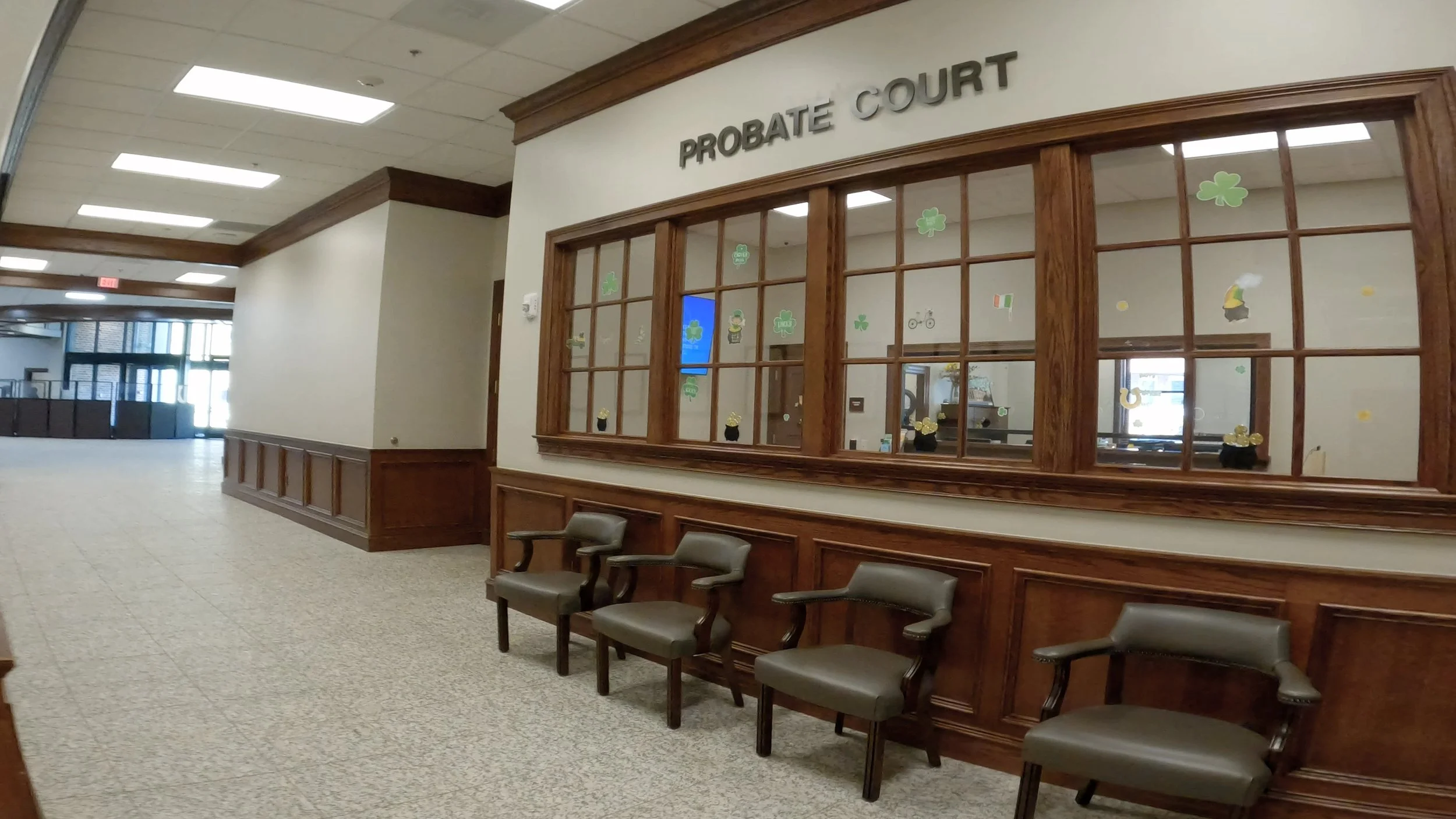Several chairs sit empty underneath probate court welcome windows.