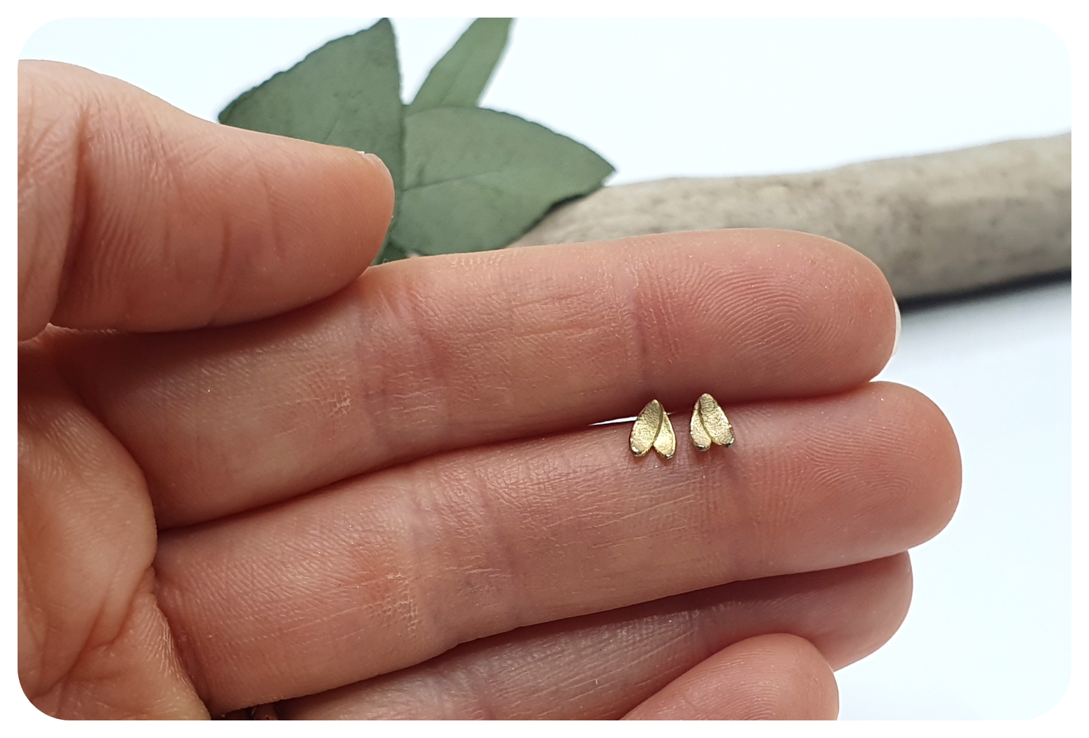 tiny gold double petal earrings in hand.png