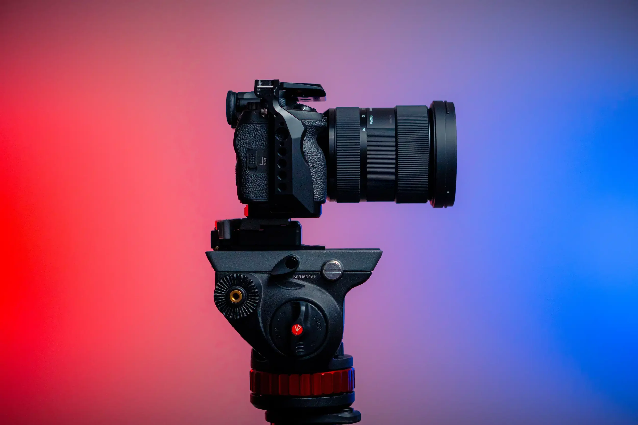 A camera mounted on a gimbal against a background with red, pink, and blue gradient.