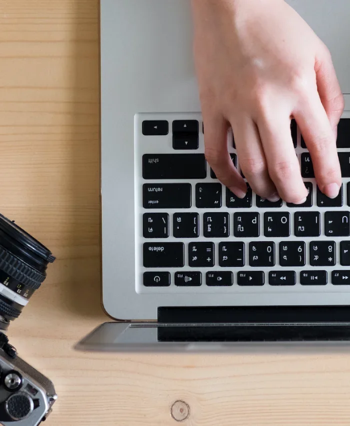 Person writing on laptop and camera on the left side