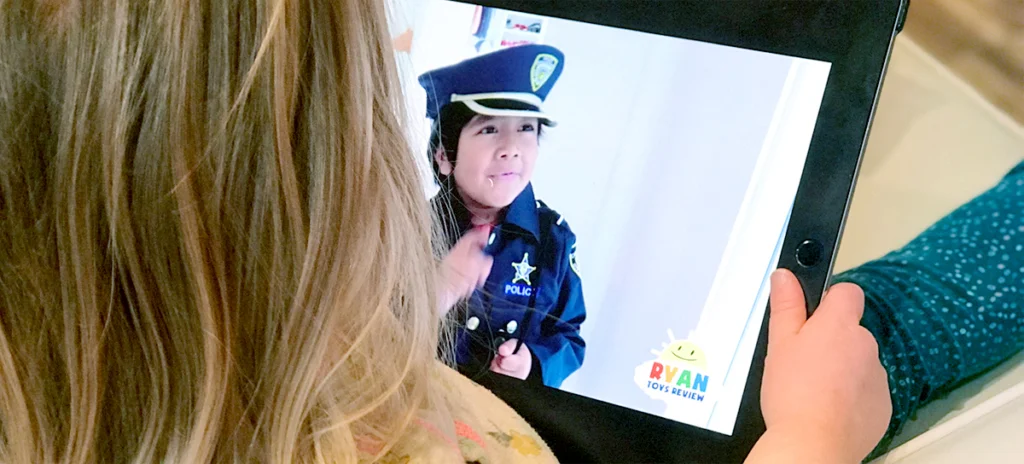 Image of a young girl with an ipad on her lap viewing Ryan of Ryan Toys Review.