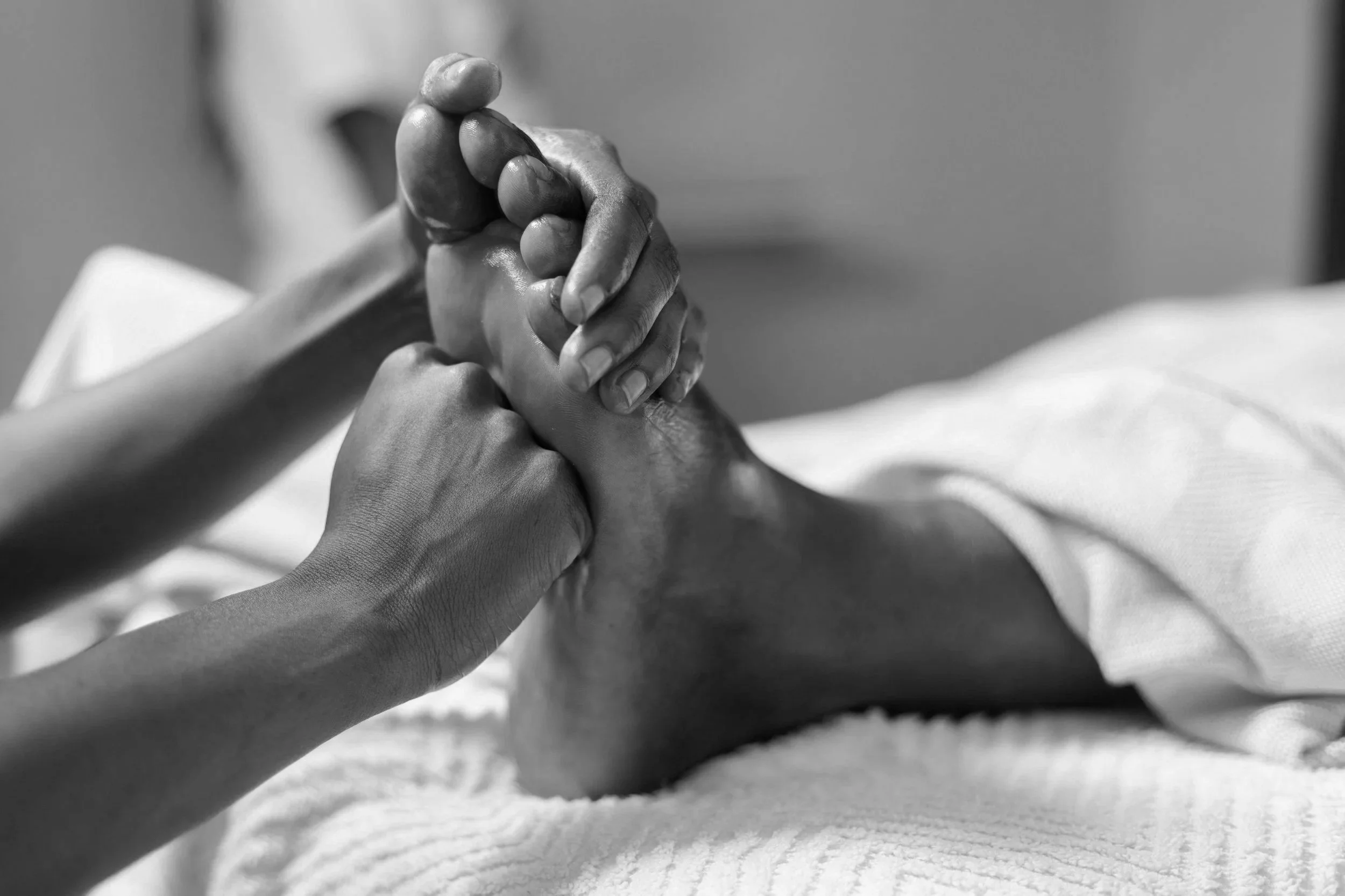 Two hands clasped in a supportive gesture, one hand resting on another, in a black and white photo.