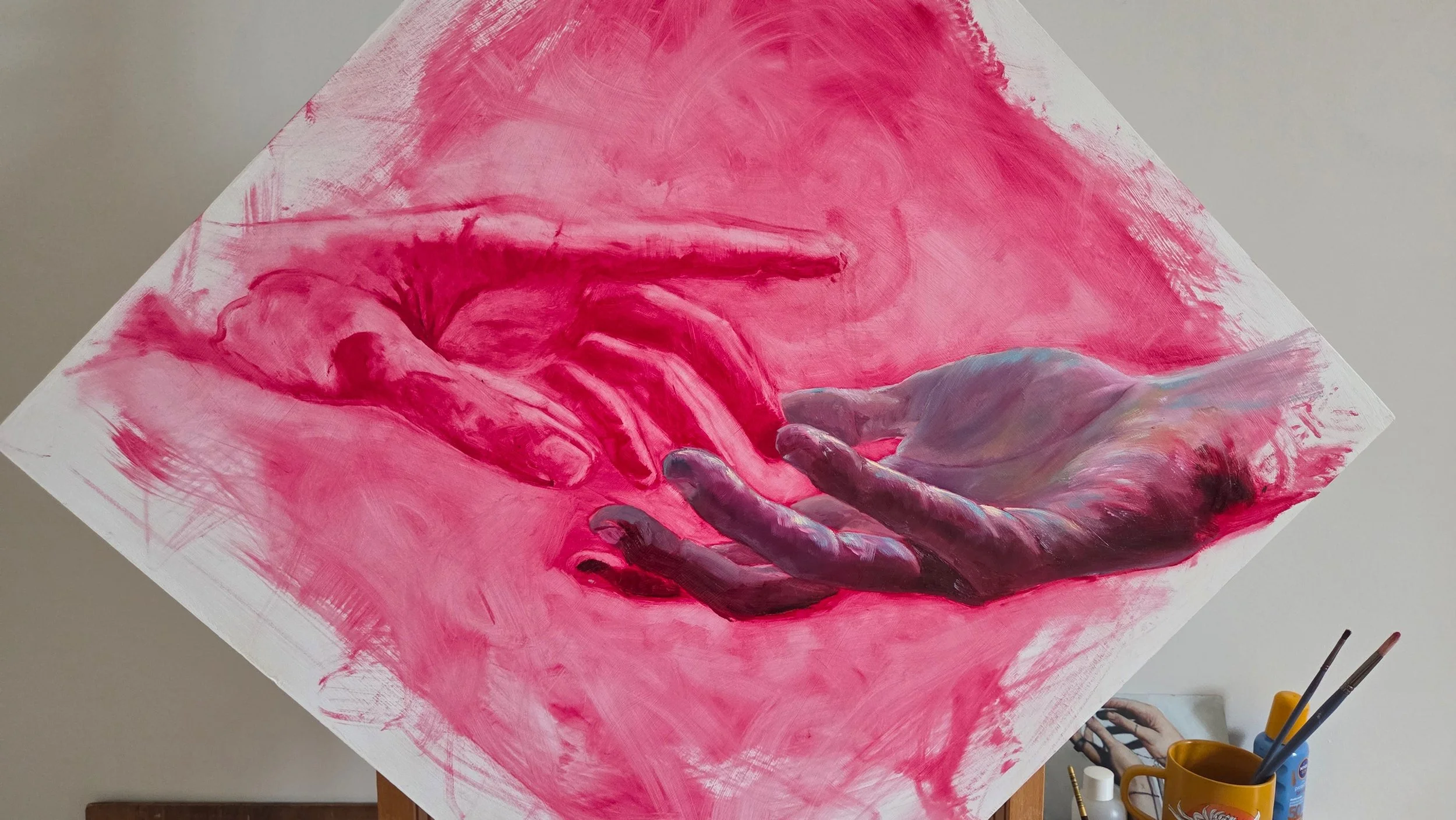 A painting in progress of two hands reaching towards each other, rendered in pink and purple tones, with expressive brushstrokes.