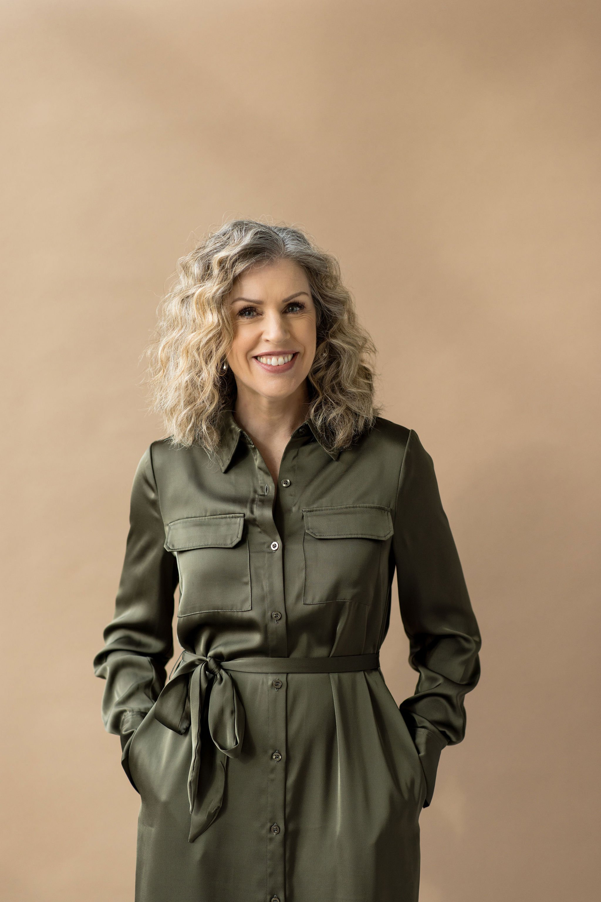 Dana Van Nest smiling at the camera in an olive green dress