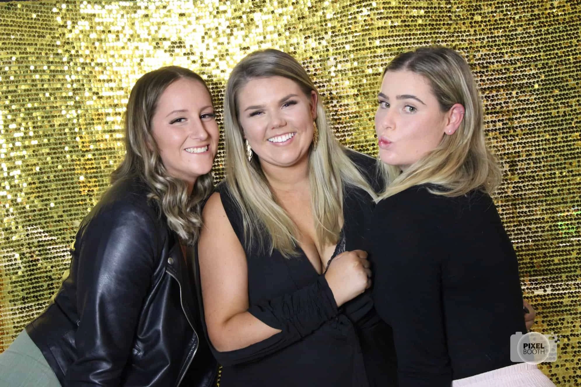 Guests posing in front of gold photo booth backdrop
