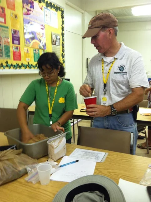 Oahu Master Gardeners following the instructions on making EM Bokashi and checking for right moisture content.