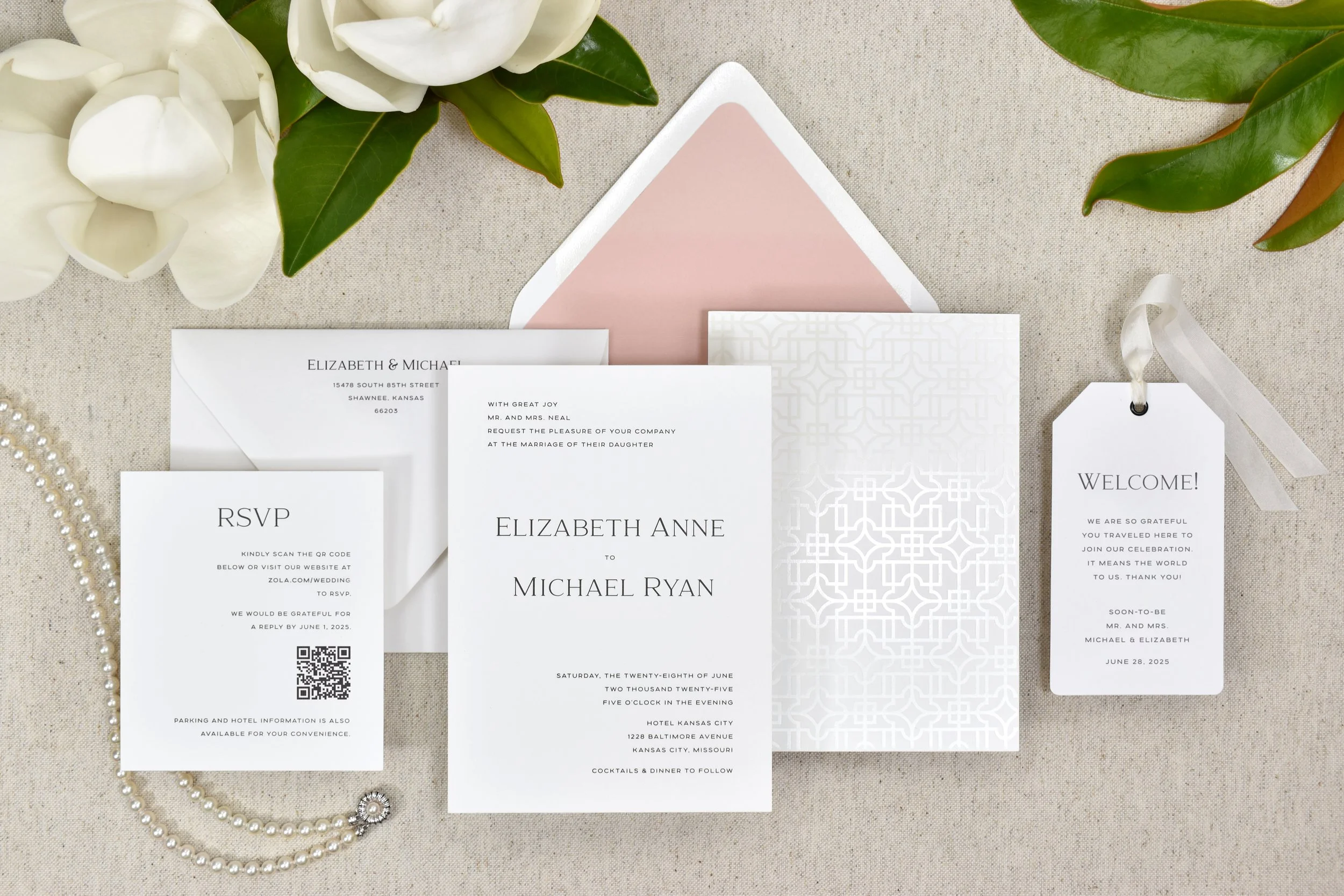 Black and white invitations with a rose envelope liner and pearl foil, with a pearl necklace and magnolia blossoms.