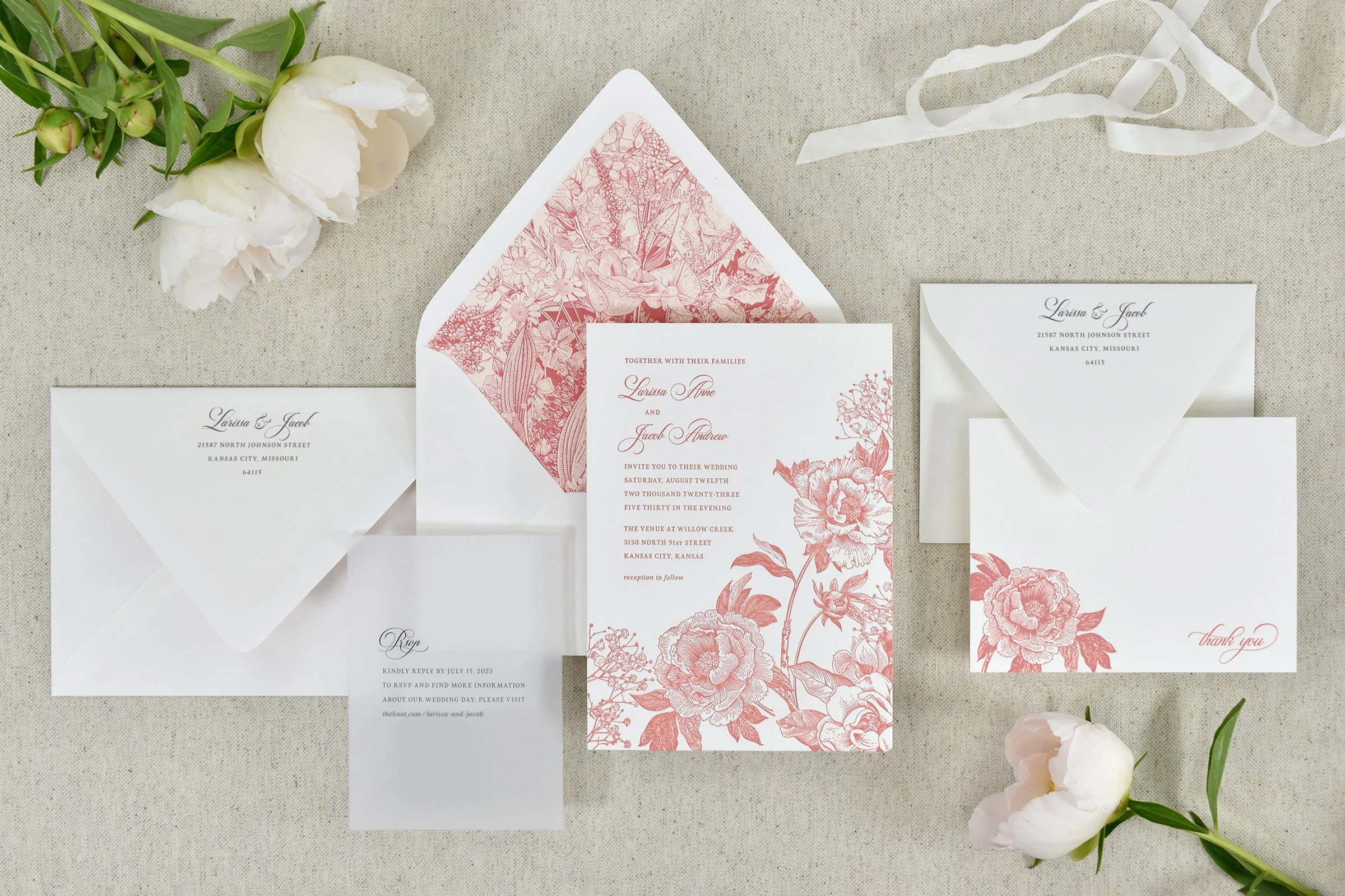A wedding invitation suite with pink and white flowers.