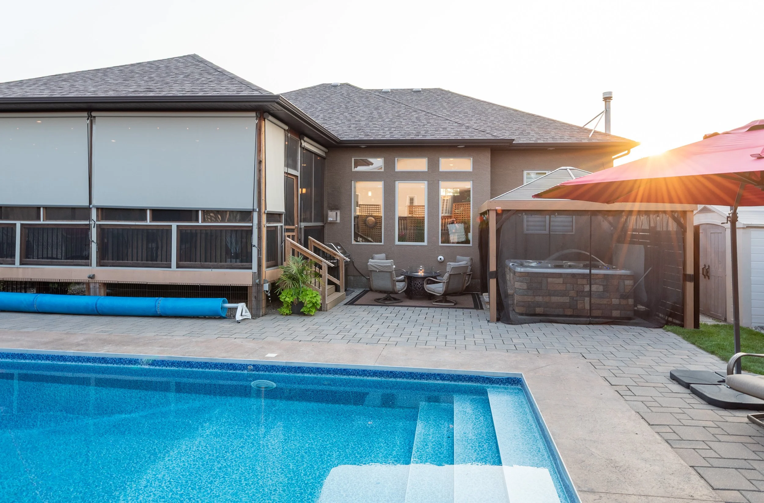 Backyard with a swimming pool, patio area with outdoor furniture, hot tub with canopy, and a house with a screened porch and large windows