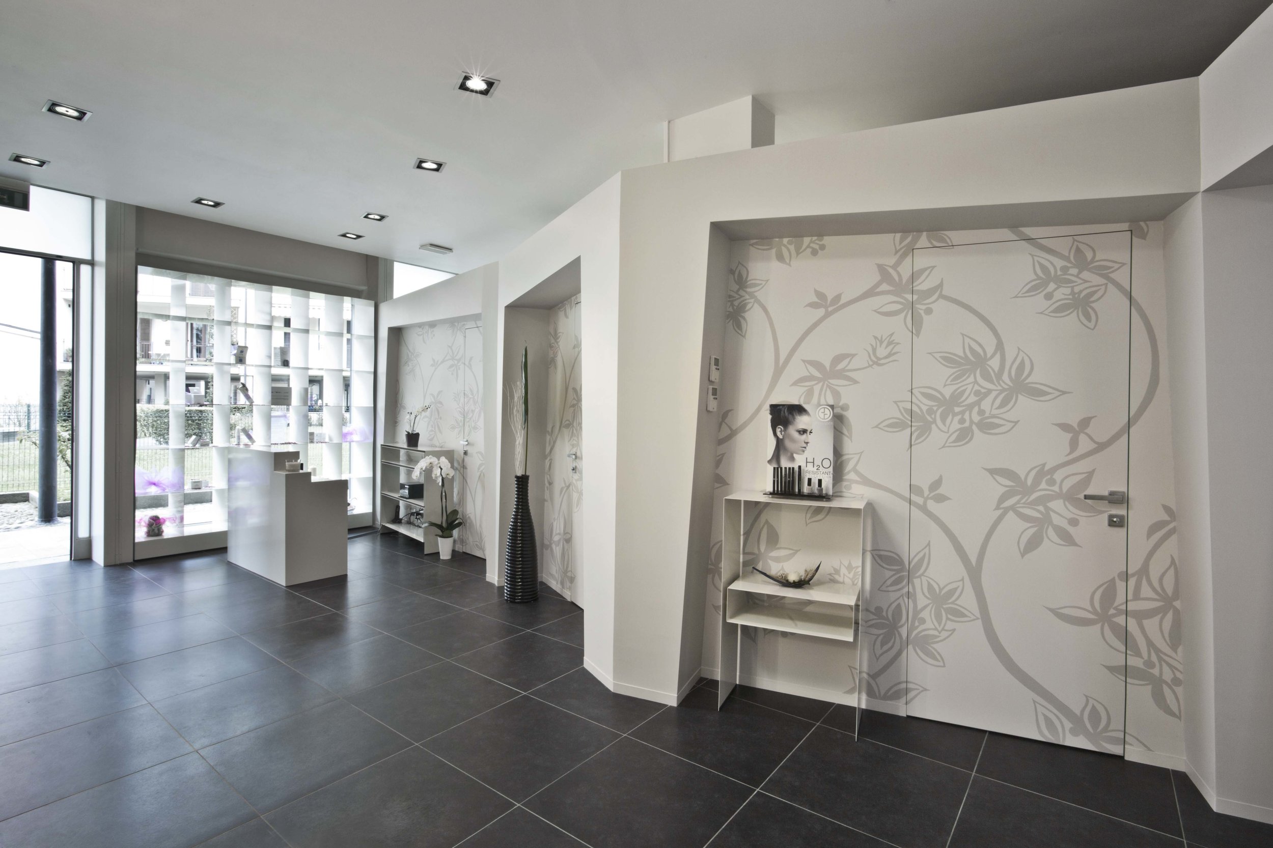  Il cliente viene accolto in una stanza che si sviluppa verso la zona operativa del centro attraverso un cannocchiale distributivo delimitato da quattro portali di accesso alle sale di trattamento. Le zone di accoglienza e distribuzione si sovrappong