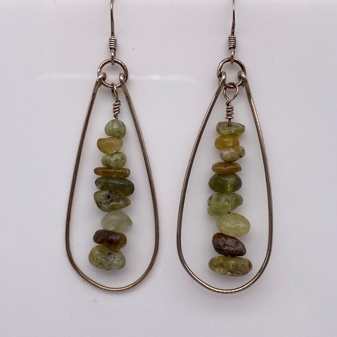 In tune with the 4th Chakra, green Garnets are thought to cleanse the heart so that we may be more empathetic of others and ourselves.

Reminiscent of teardrops, eight green Garnet chips hang in the center of these 2.25&rdquo; sterling silver earring