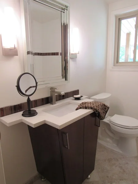 The full remodel of this very narrow bathroom vanity detail that allows the door to close and still allows room on the quartz counter top. The vertical tile back splash is used in the tub as well.