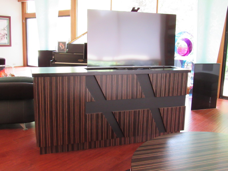 Building a custom TV unit in zebra wood that houses the audio/video and is finished on all four sides divides the seating areas in this room. The TV disappears inside when not in use.