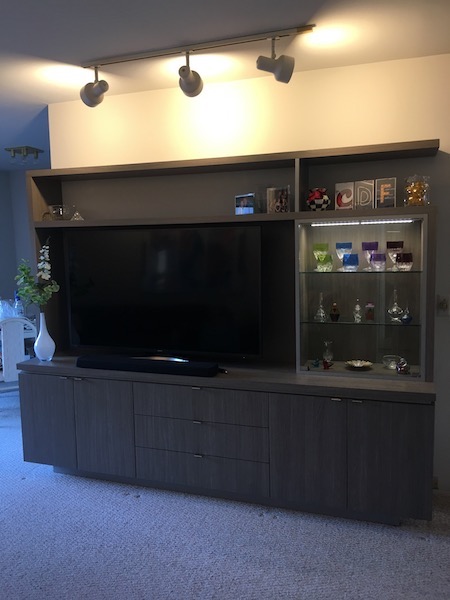 A custom wall unit was designed to hold a big-screen TV, easy closed audio accessibility, storage, open display and glass-enclosed and lighted closed display for a wow factor!